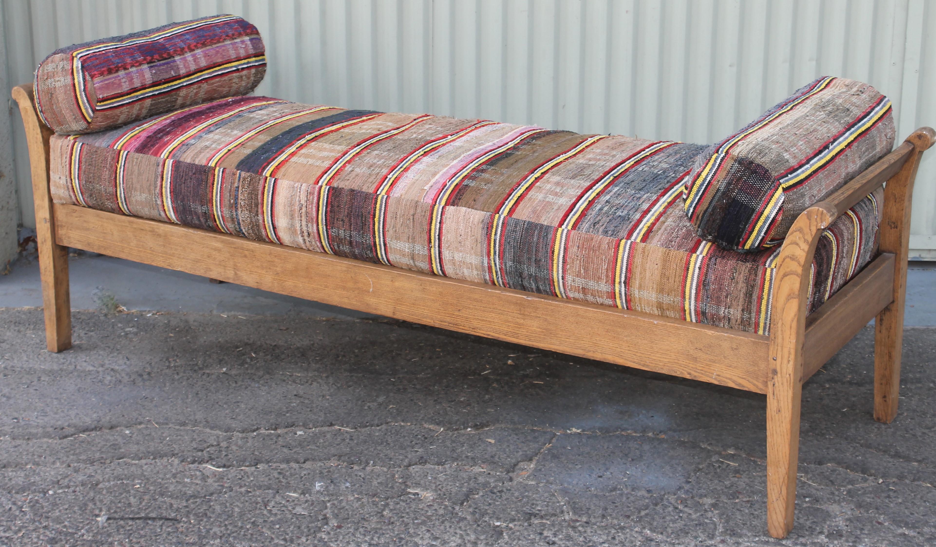 This amazing 19thc day bed is upholstered in 19thc rag rug cushion and two round pillows. The inserts are foam core with a down filled envelope insert. All removable for cleaning.