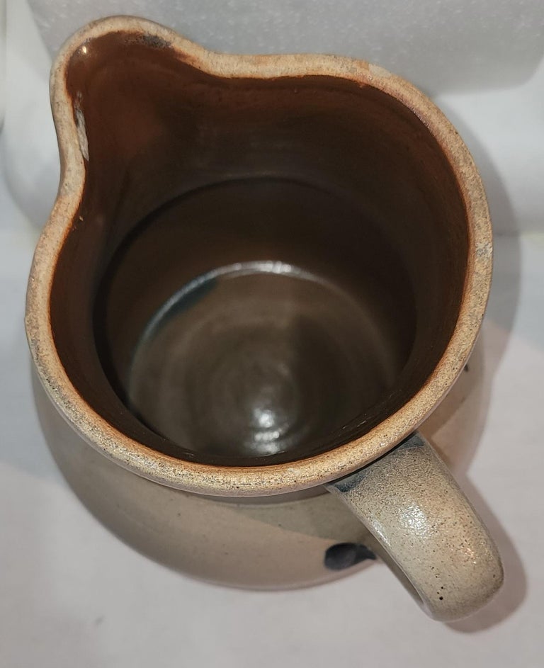 This fine hand made decorated stone ware pottery pitcher is made by Cowden & Wilcox in Harrisburg,Pennsylvania.These mis 19thc potters were very well known for decorated stoneware.This fine folk art design pottery has a snow flake design and is in