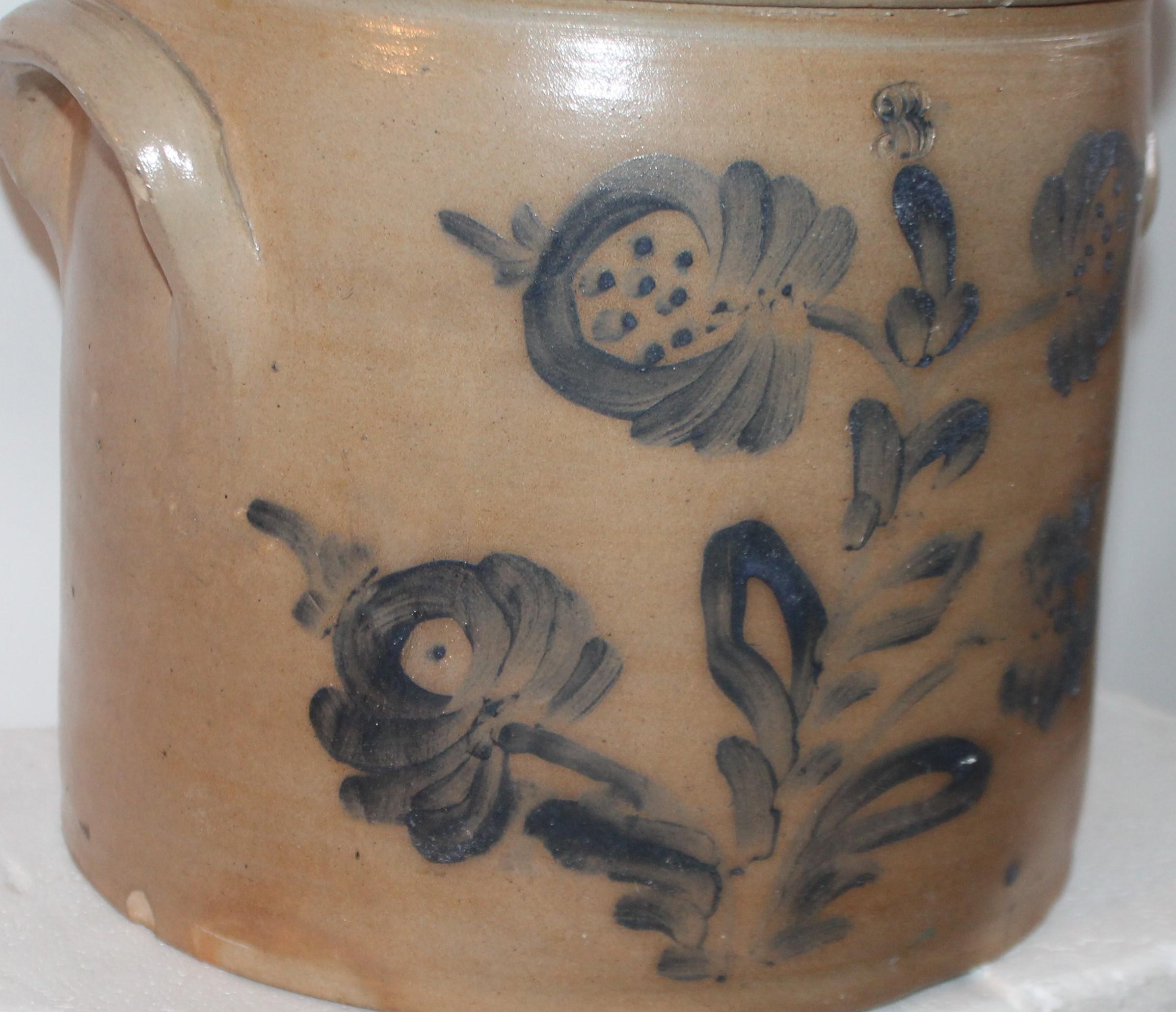 This fine double handled blue decorated stone ware crock is in good condition with minor chip on interior. There is an embossed three above the hand painted and decorated flowers on the face of the crock.