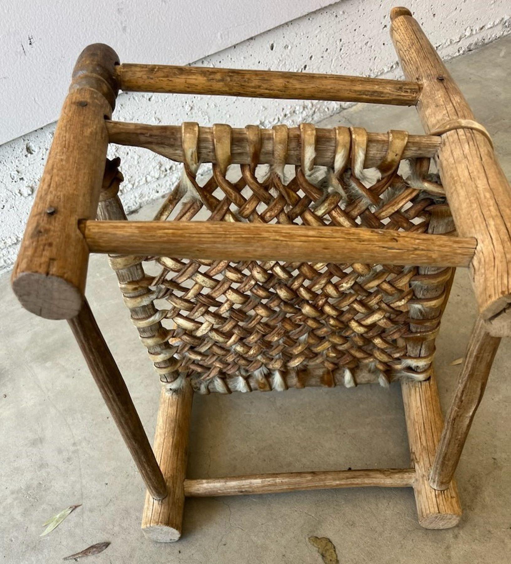This amazing early Pueblo hand made child's chair has a rawhide hand woven seat ( deer hide ). The condition is very good with a missing top slat from the ladder back top of the chair.