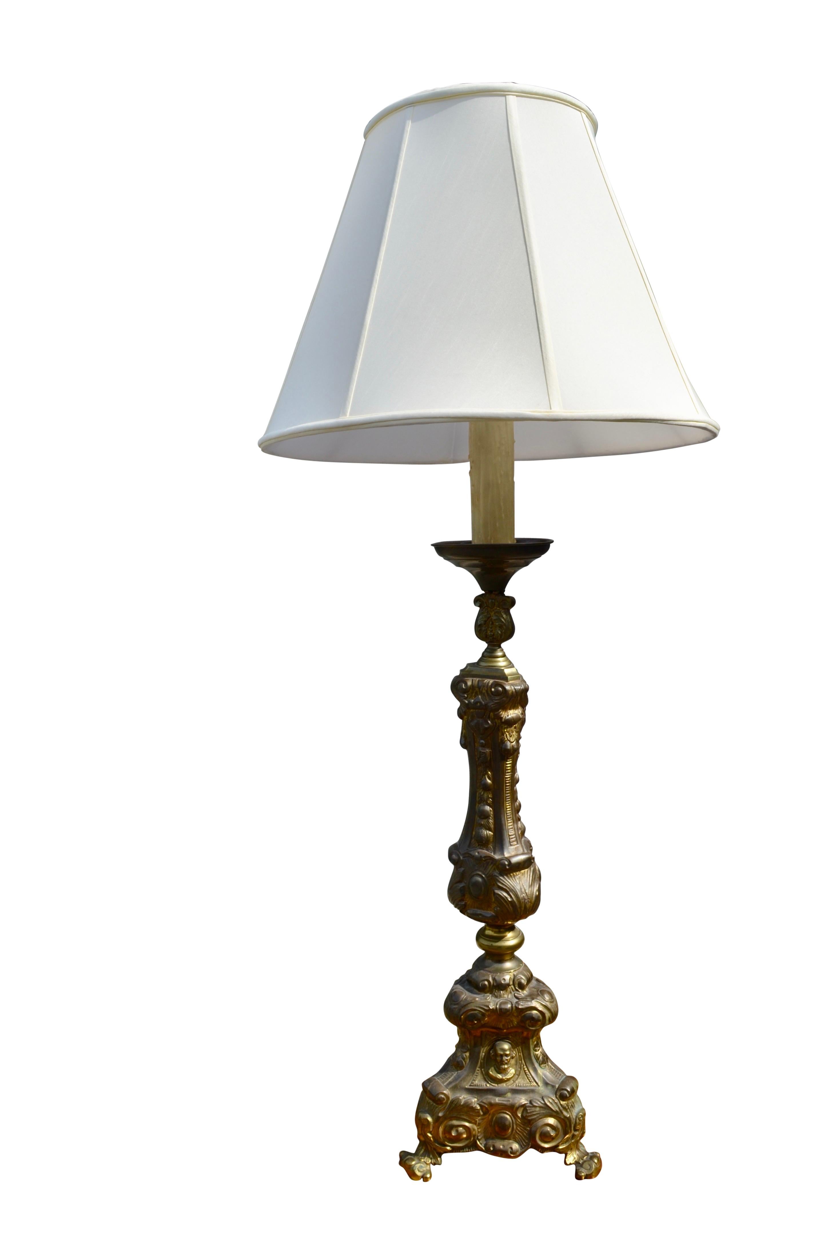 A large hollow triangular brass church candlestick now converted into a lamp. There are four sections of assembled brass excluding a top cup which holds a 10