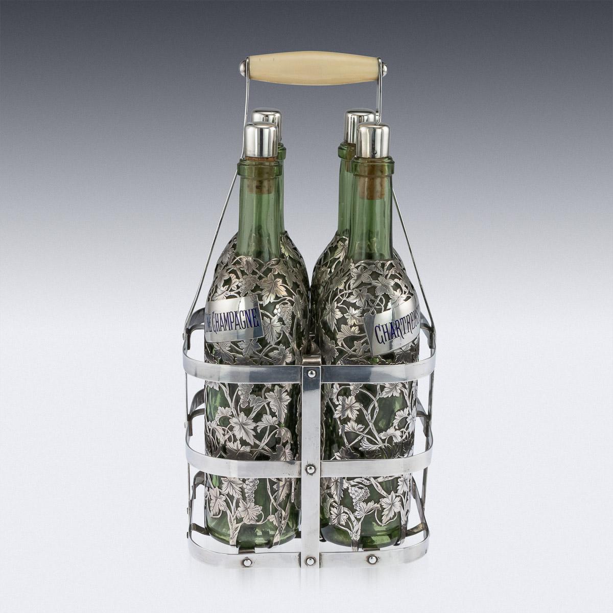 Antique late 19th century French four bottle Tantalus, green glass applied with pierced silver depicting grapevine and grapes, with fine engraved details. The plain rectangular labels are engraved with various drinks (Curacao, Anisette, Chartreuse