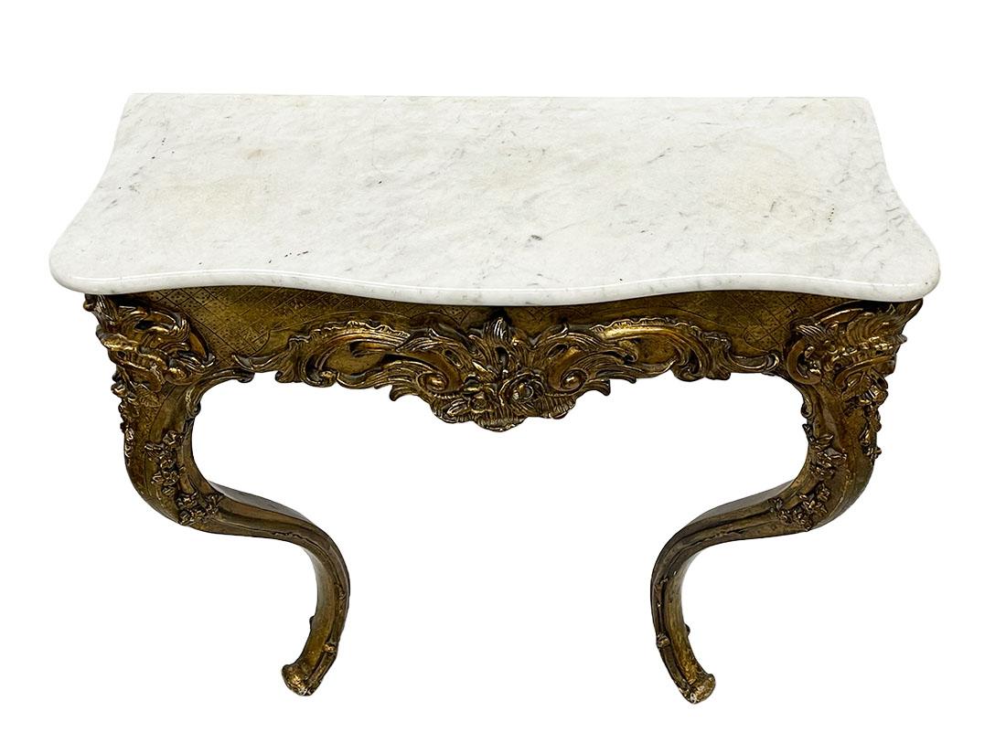 19th century French giltwood console table with marble top

A giltwood French console table with capriole legs and a white and gray marble top. The wood on the front and both legs are decorated with flower and leaf motifs. The table shows some
