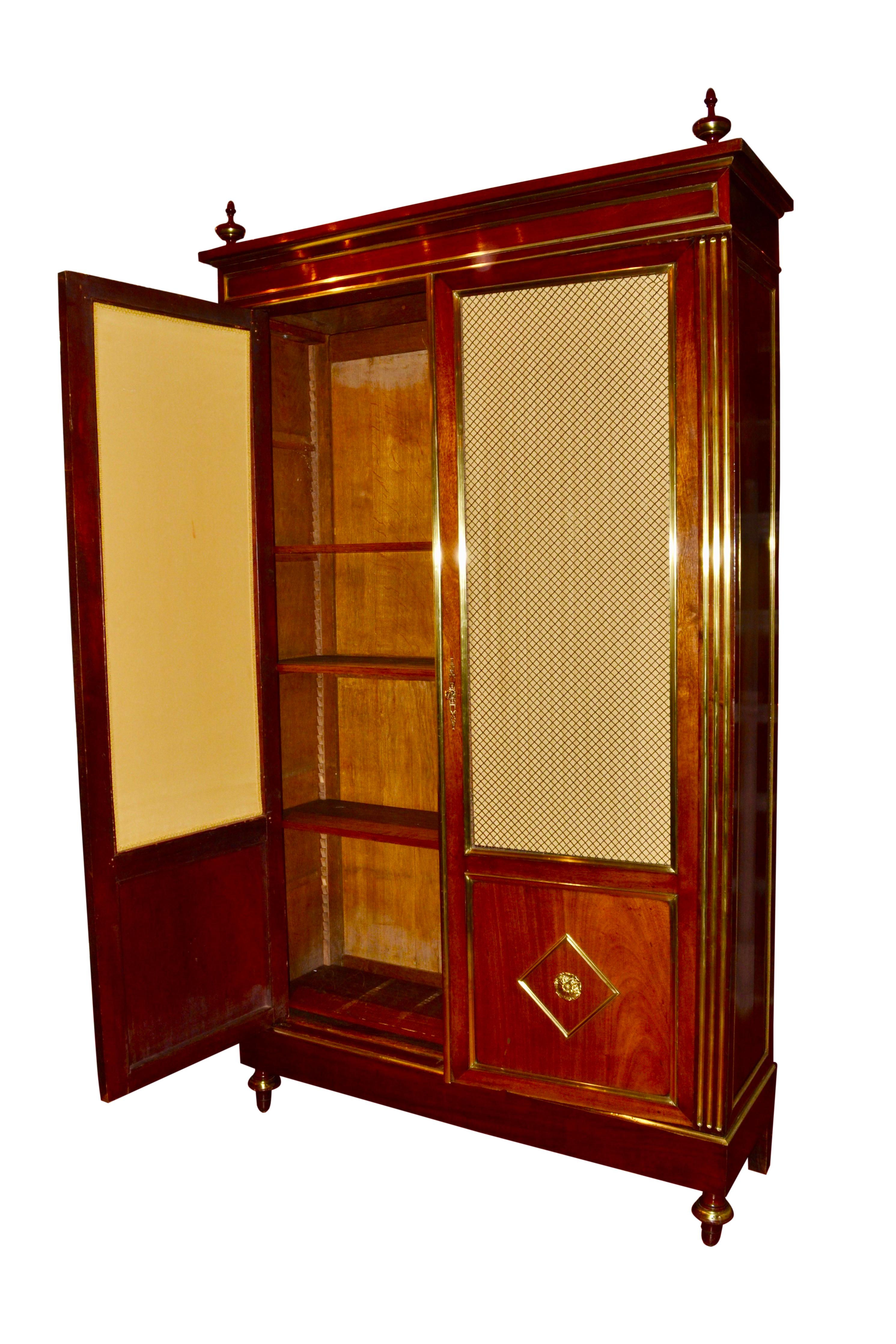 An elegant Louis XVI style bookcase/display case, the mahogany case richly inlaid with gilded brass fillets to the two front doors and both sides, Each door has a three quarter panel of open brass grill work over the lower quarter panel centered