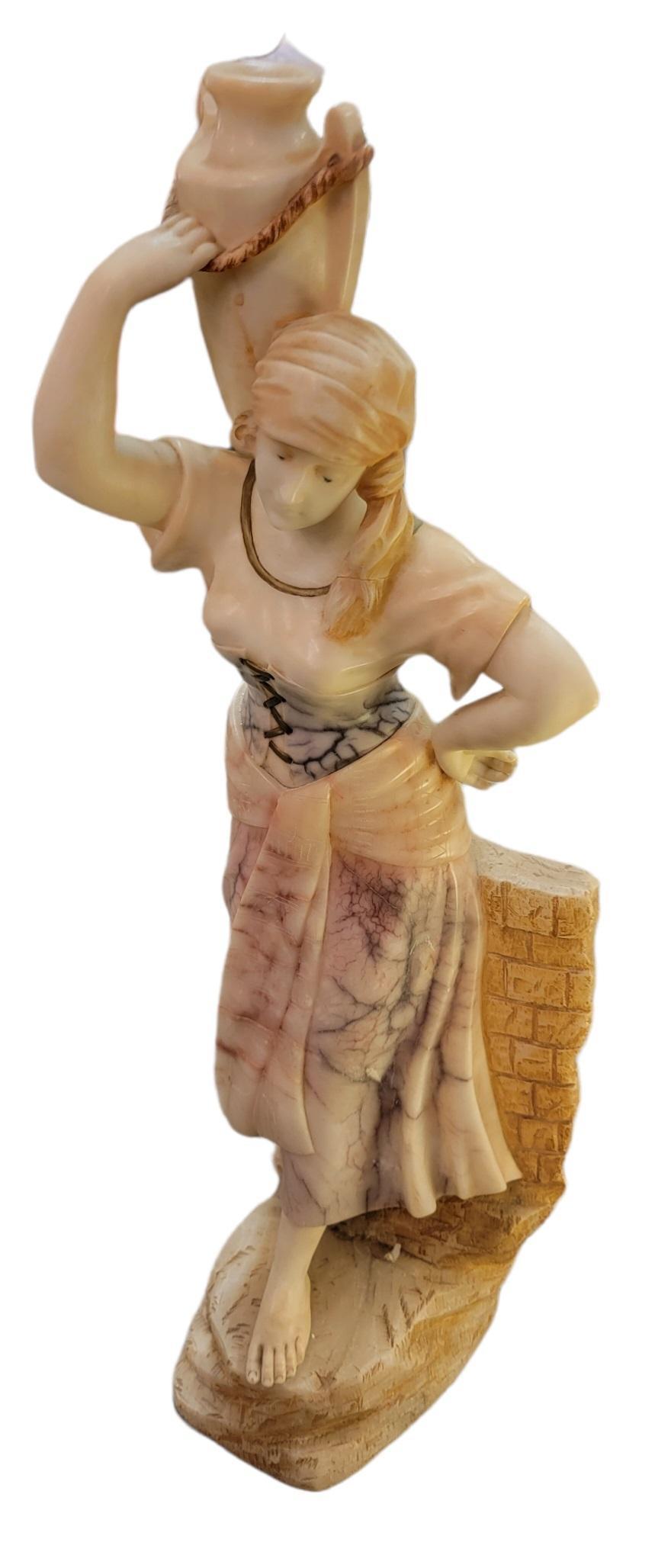 Statue de femme en albâtre sculpté à la main, en marbre, tenant un vase/canister, pieds nus et vêtue d'un costume de travail traditionnel. Base lourde. Article lourd.