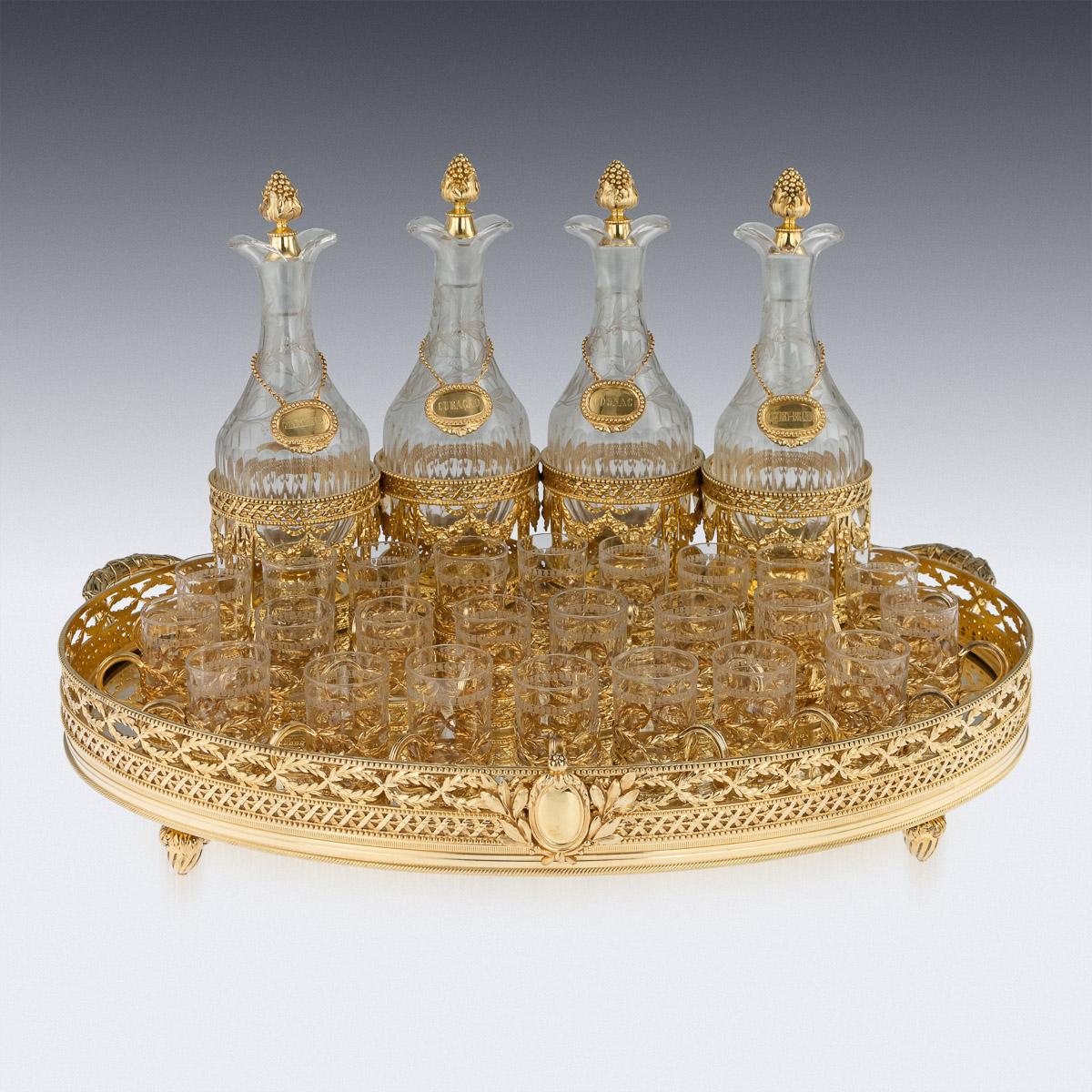 Antique late-19th century French exquisite solid silver-gilt liqueur service, consisting of 4 liqueur bottles, 24 cups, 4 labels and a mirror set serving tray. Made in the Louis XVI style decorated with pronounced beaded boarders, laurel garlands