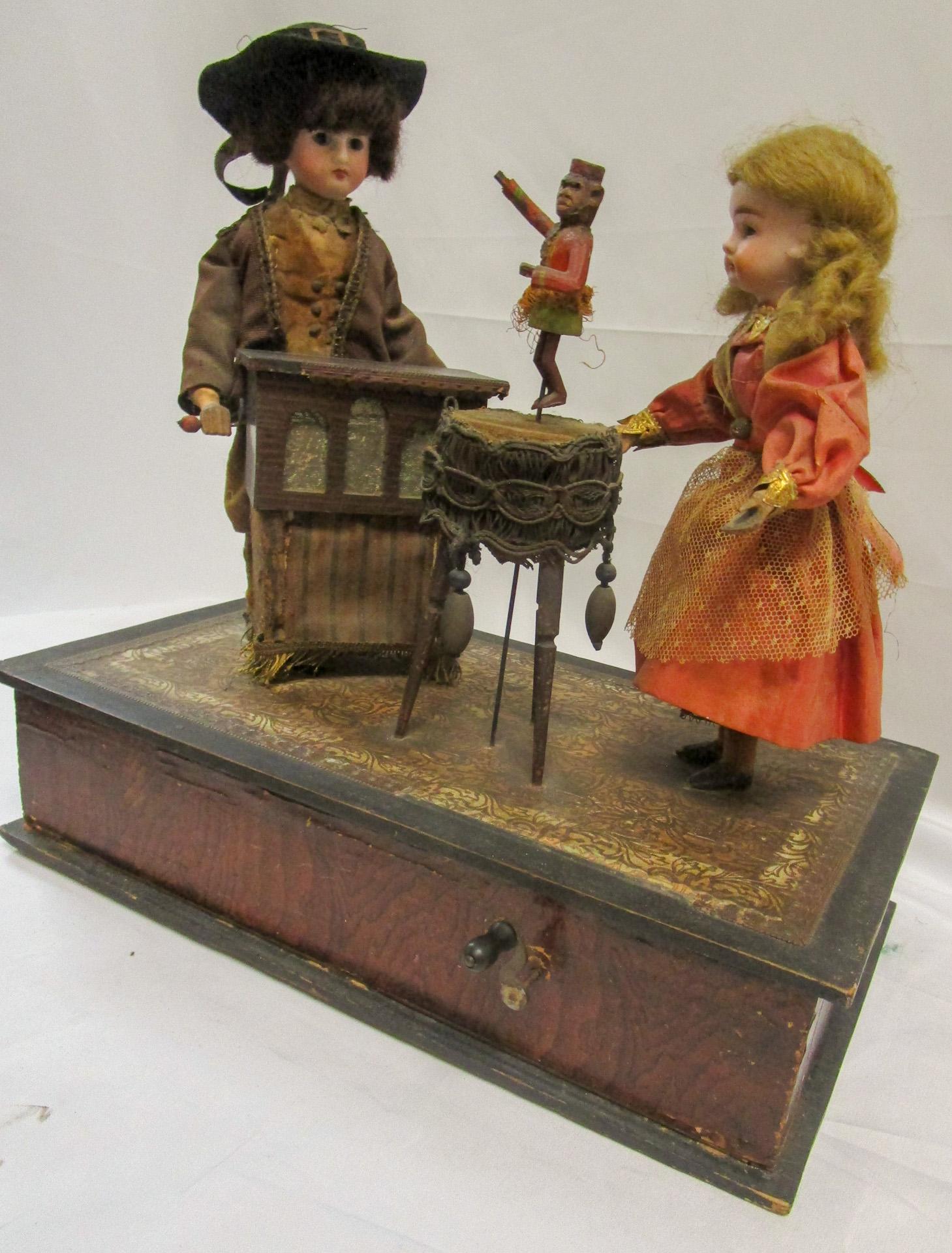 This rare playful presentation features wonderful detailed faces, charming actions and whimsical music. Arranged on a faux bois paper covered wooden platform, a young organ grinder and his monkey entertain a little girl. When wound, a merry tune is