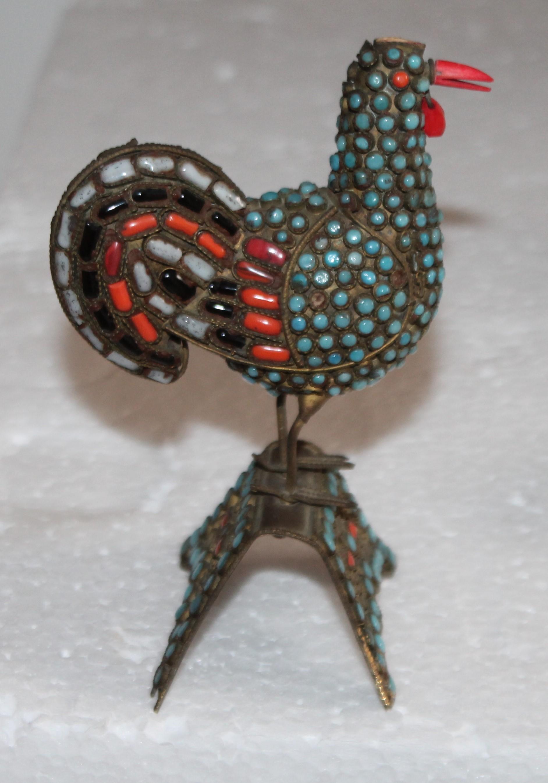 This handmade brass bird has inlaid coral and turquoise with small flakes of amethyst and shell. The work details are really amazing. It stands on its own brass inlaid perch or stand.