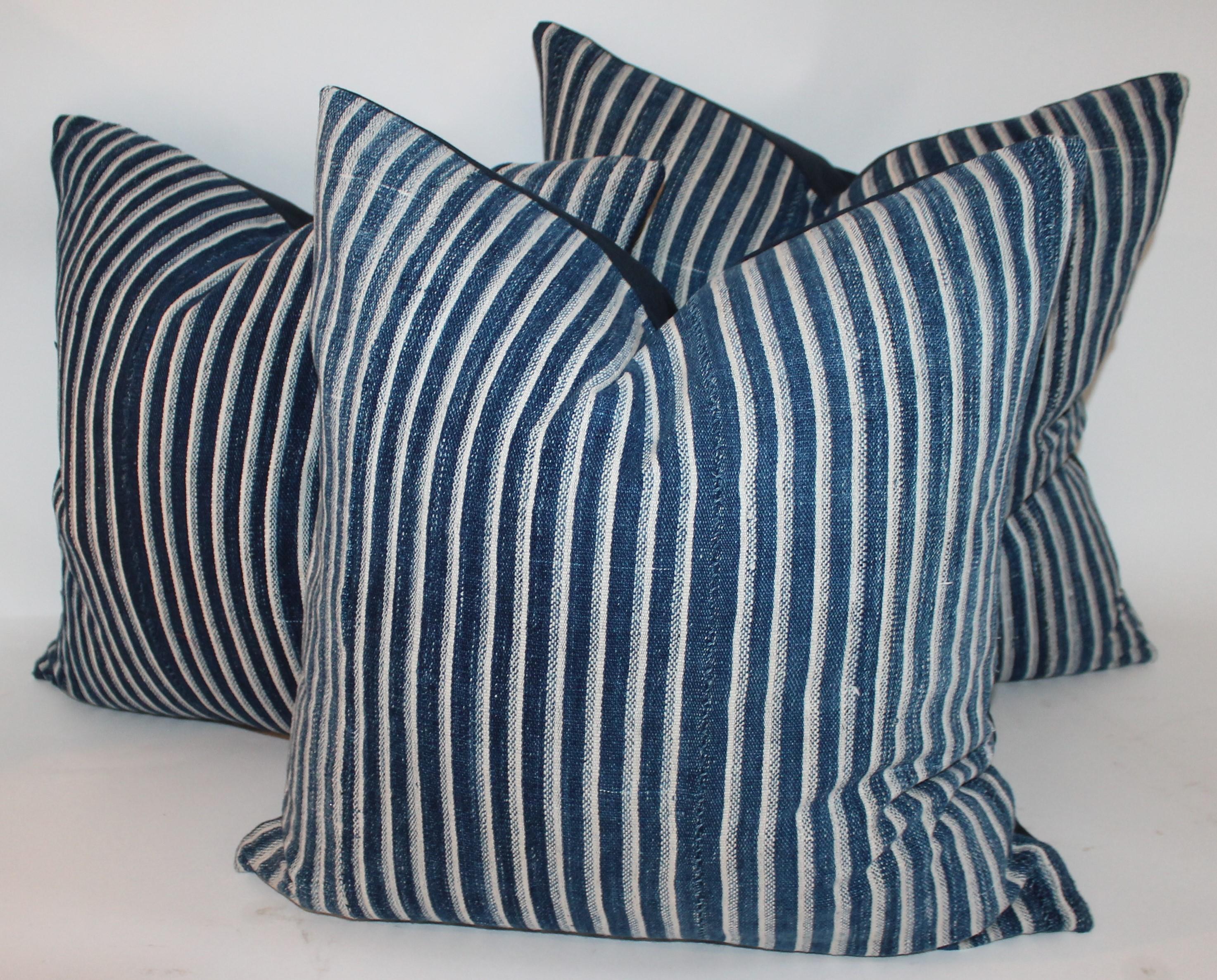 Collection of three deep blue striped linen ticking pillows. The backings are in dark blue cotton linen fabric. The inserts are down and feather fill.
