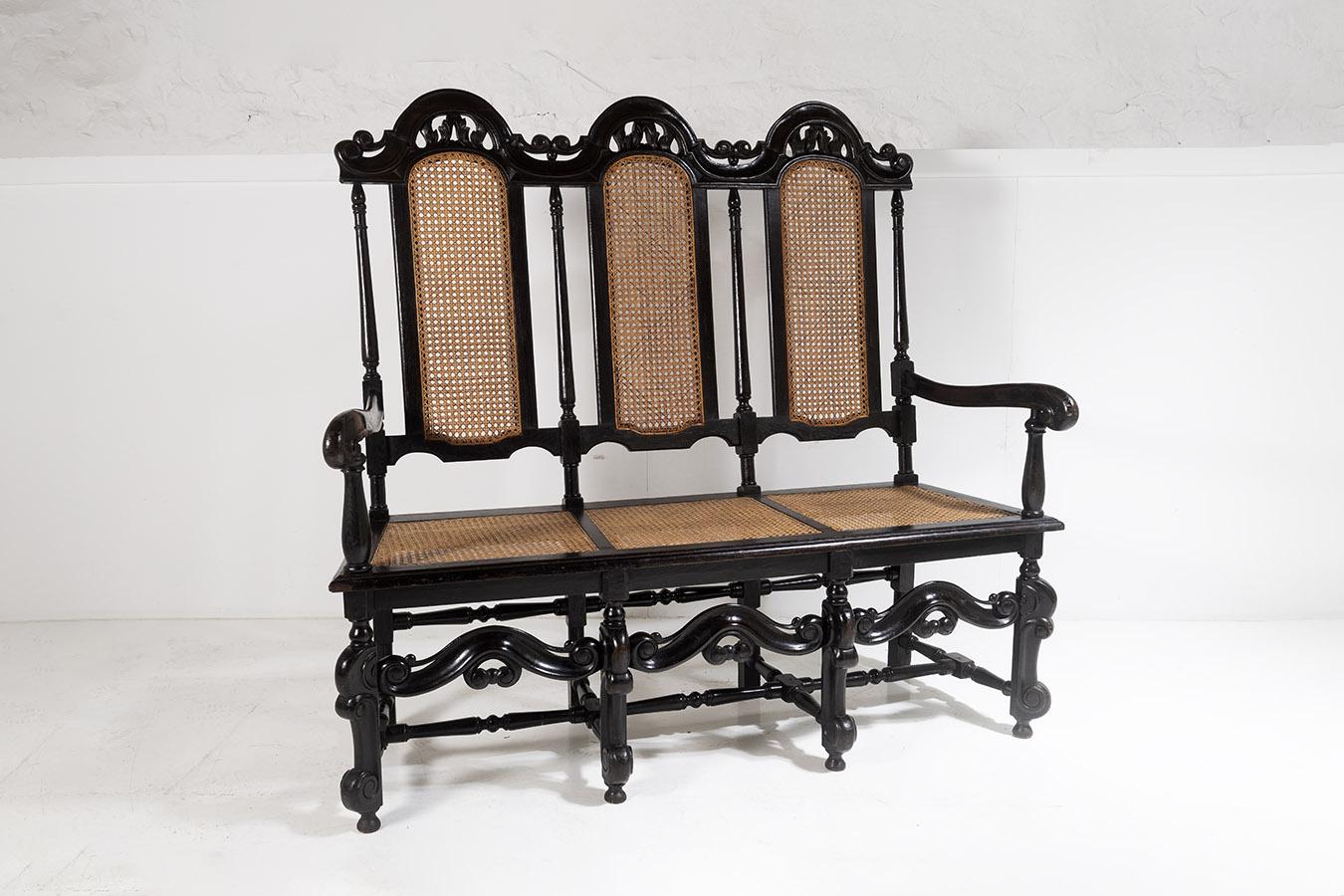 A decorative and well presented 19th Century Jacobean renaissance carved oak three seater high back bench settee.  A superb quality piece with ornate arched back and cane inset panels. A lovely contrast with dark, almost ebonised wood frame, and