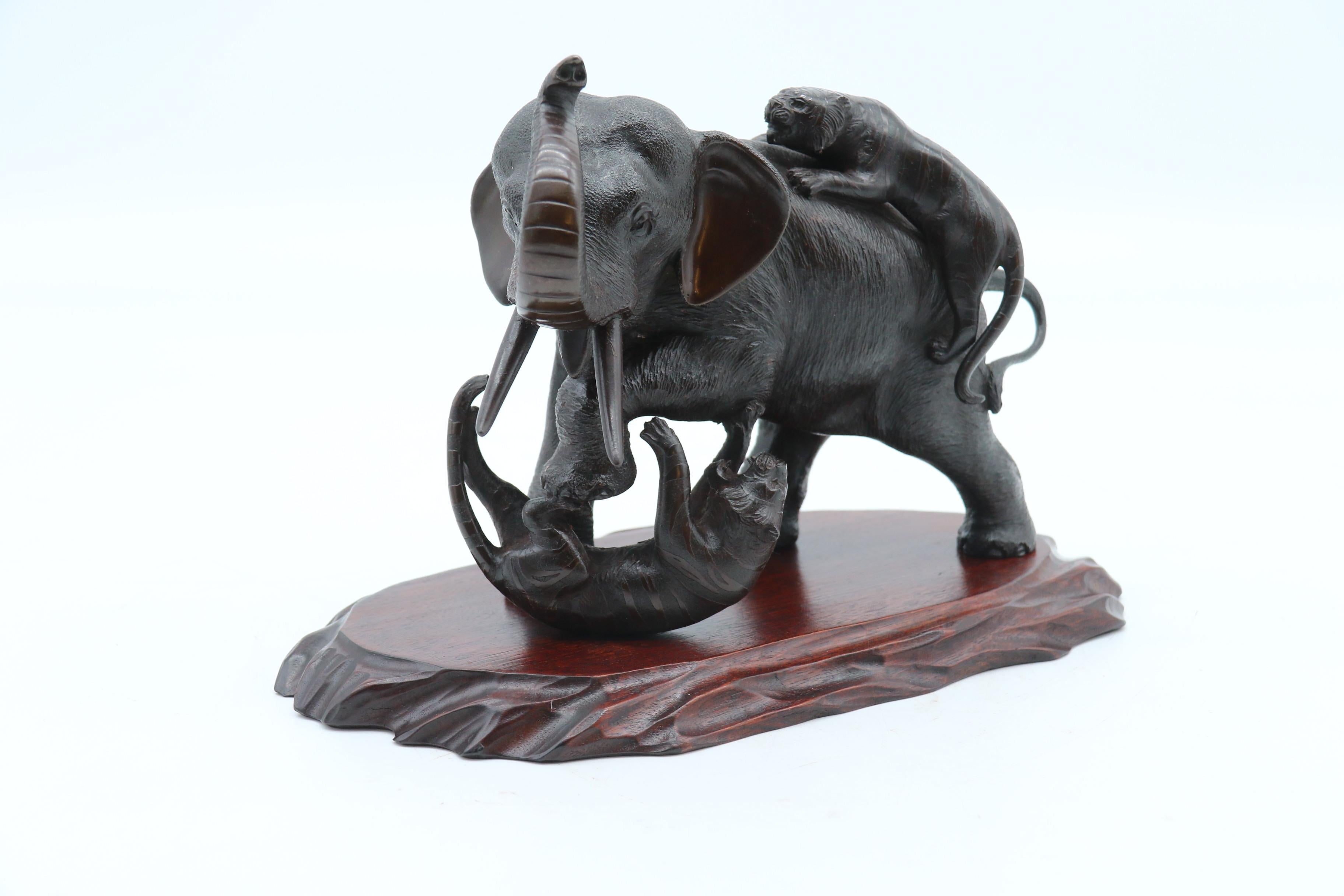 This superb Japanese Meiji period bronze study has exceptionally good detailing. It portrays a figure group of a large muscular bull elephant being attacked and fighting with two tigers. One is clinging to his back and the other has been knocked to