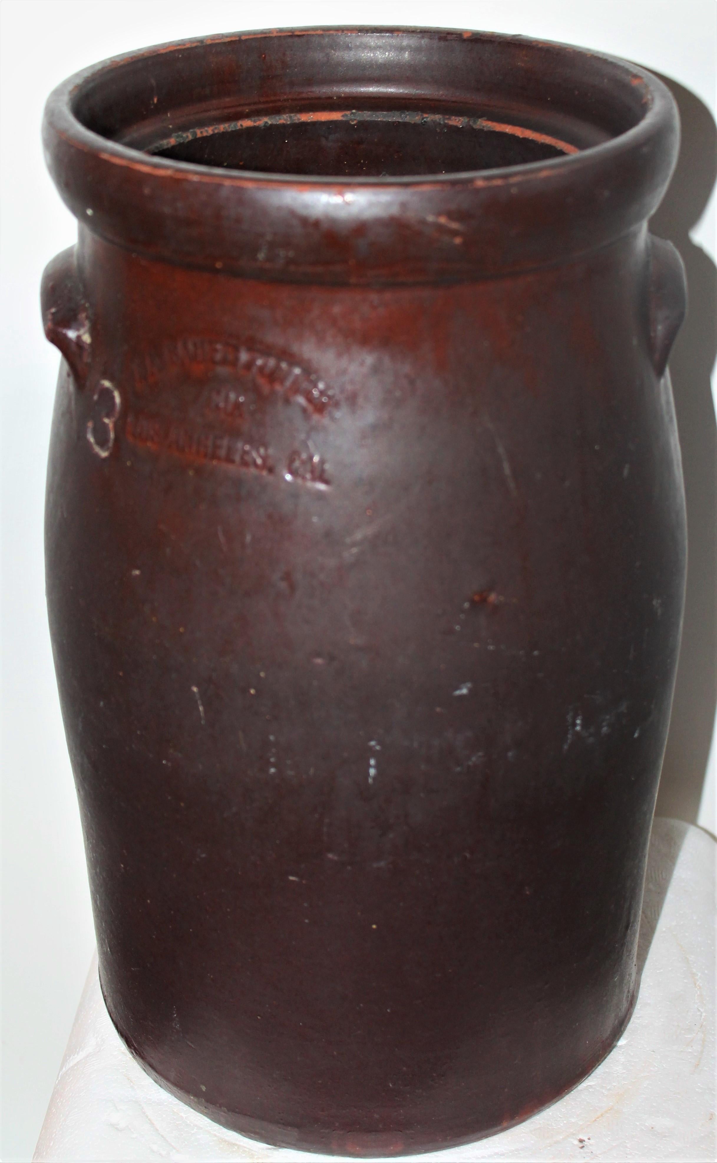 This 19th century red cay glazed crock has double handles and is signed Los Angeles. It has double handles and a chocolate brown finish. The condition is good and it is signed LA BAUER & BAUER / LOS ANGELES.
