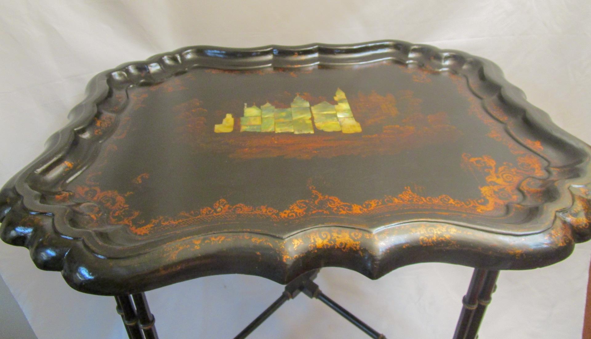 A large and rare Papier-mâché tray table with intricate view of castle in mother of pearl inlay on the top set in a serpentine shaped surround with gilded foliate borders and gold gilt border around the castle. Twelve graceful legs in sets of three