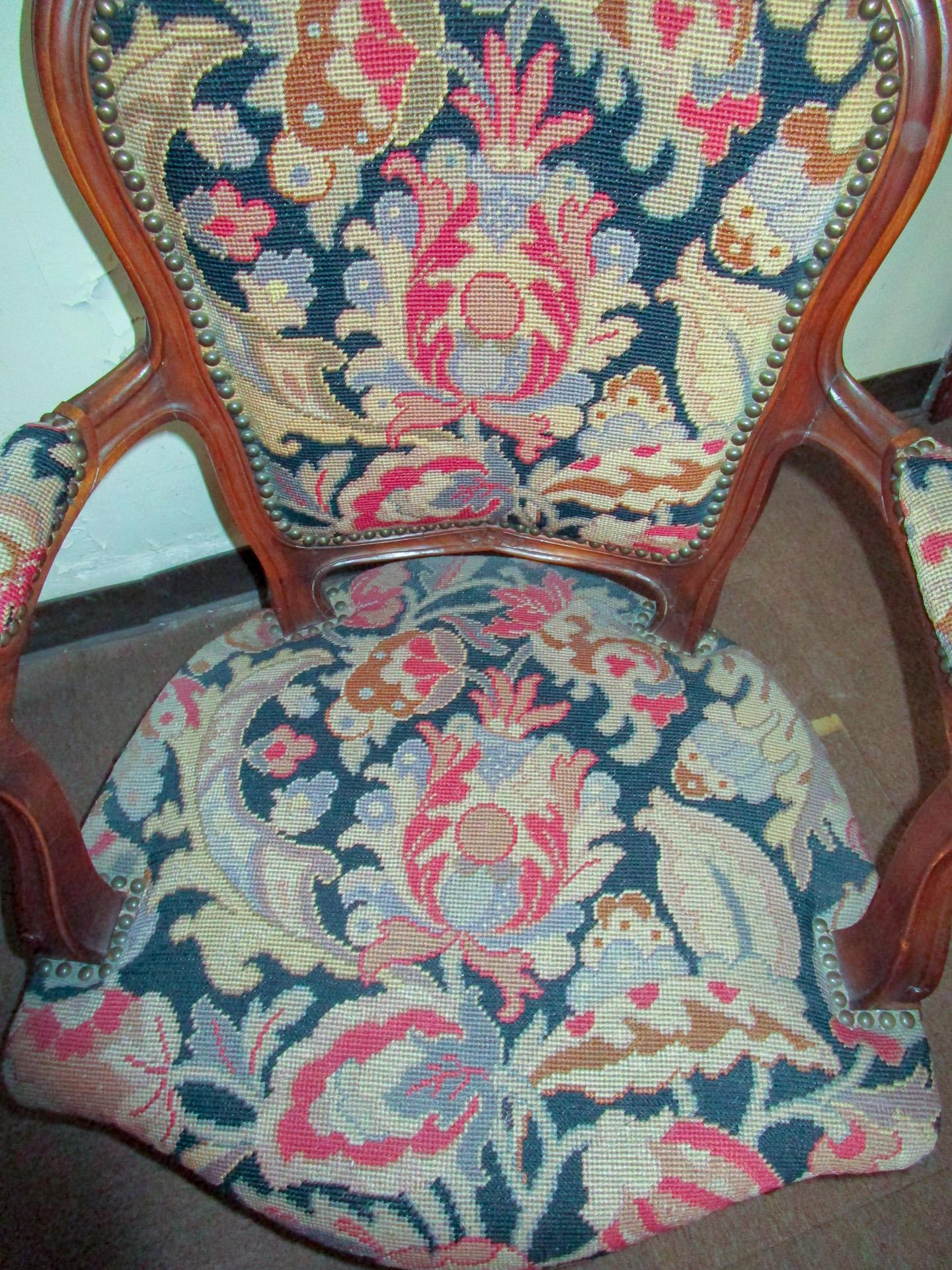 This lovely matching pair of fauteuils with walnut frames feature carved serpentine backs, arms, legs and crests with flower decoration. The gorgeous color needle point upholstery is in pink and grey shades against a stunning black background. The