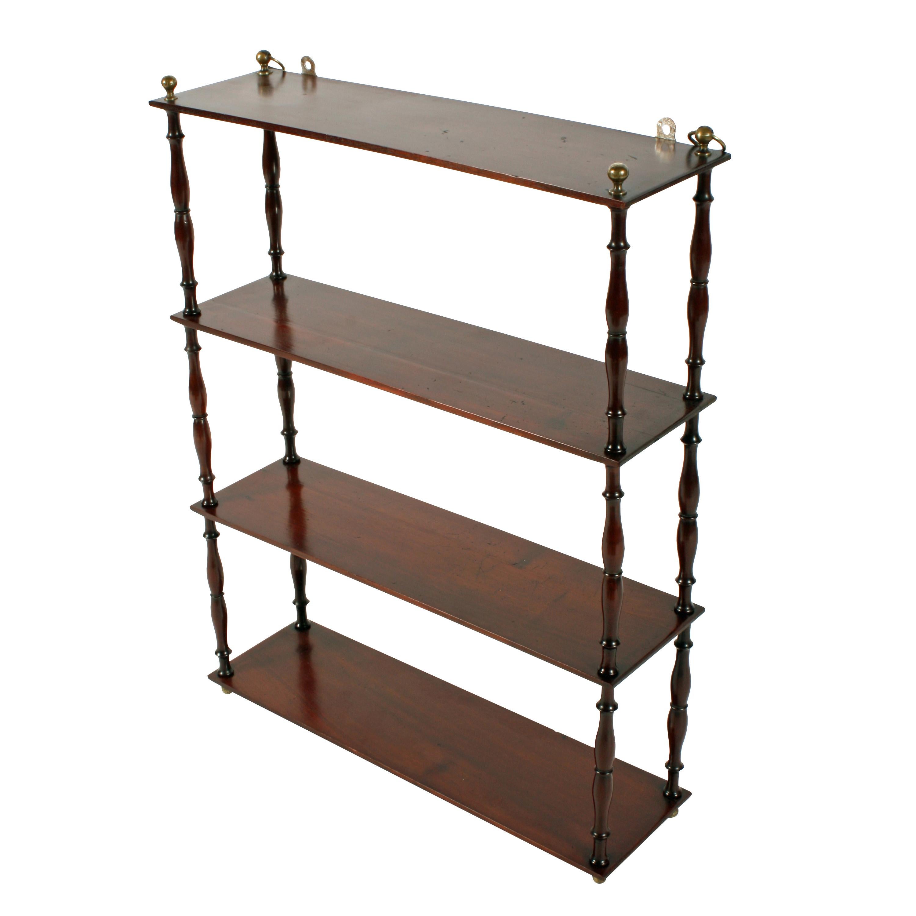 Middle of the 19th century Victorian mahogany four shelf wall hanging shelves.


The four oblong solid mahogany shelves are supported on finely turned and shaped pillars with a brass ball finial at the top.


The top shelf has brass rings from