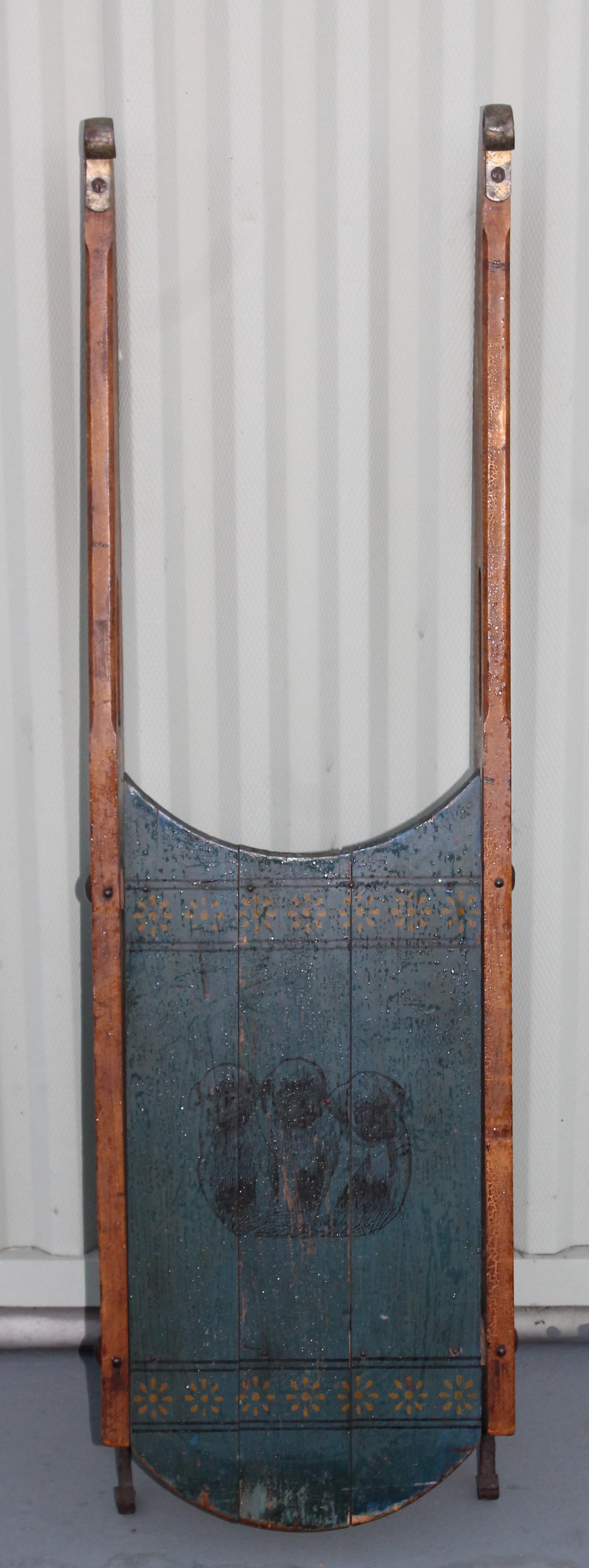 19th century original blue painted sled with three painted pugs (dogs) on the center top of the sled. There are manufacturer PMC maker marks on the side. 
On the base Paris Manufacture Company from the state of Maine. No. #6 South Pacific, Maine.