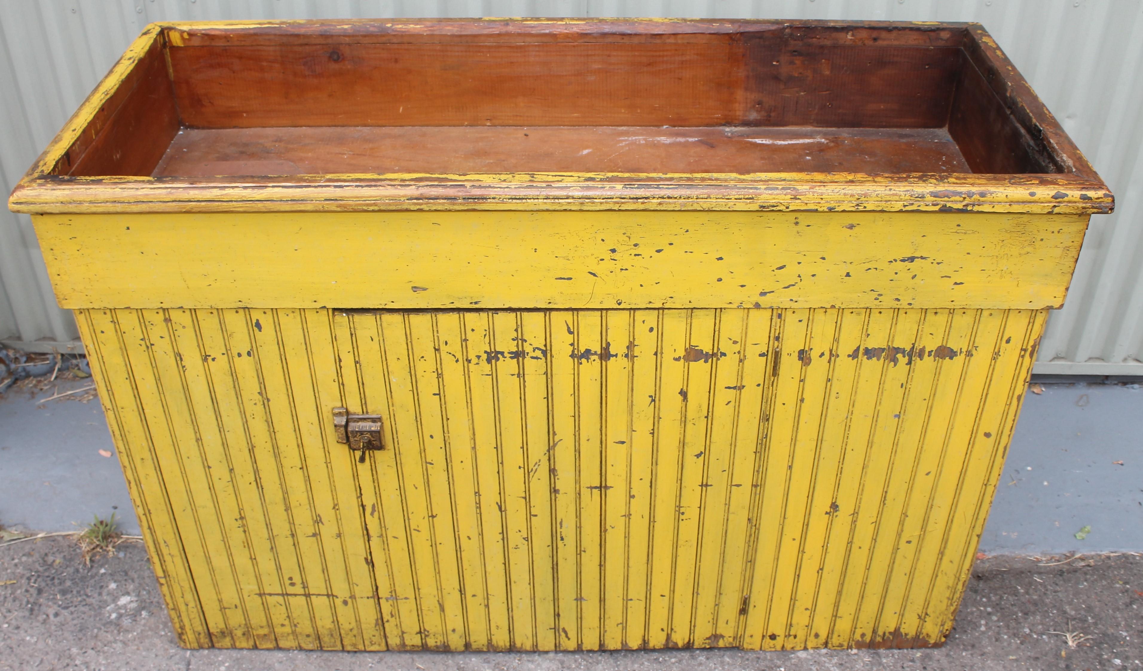 This 19th c original painted chrome yellow dry sink that is made with a wainscoting pine and painted all around the outside. The interior is painted in a salmon painted surface. The chrome yellow is painted over a grey / blue base coat paint.