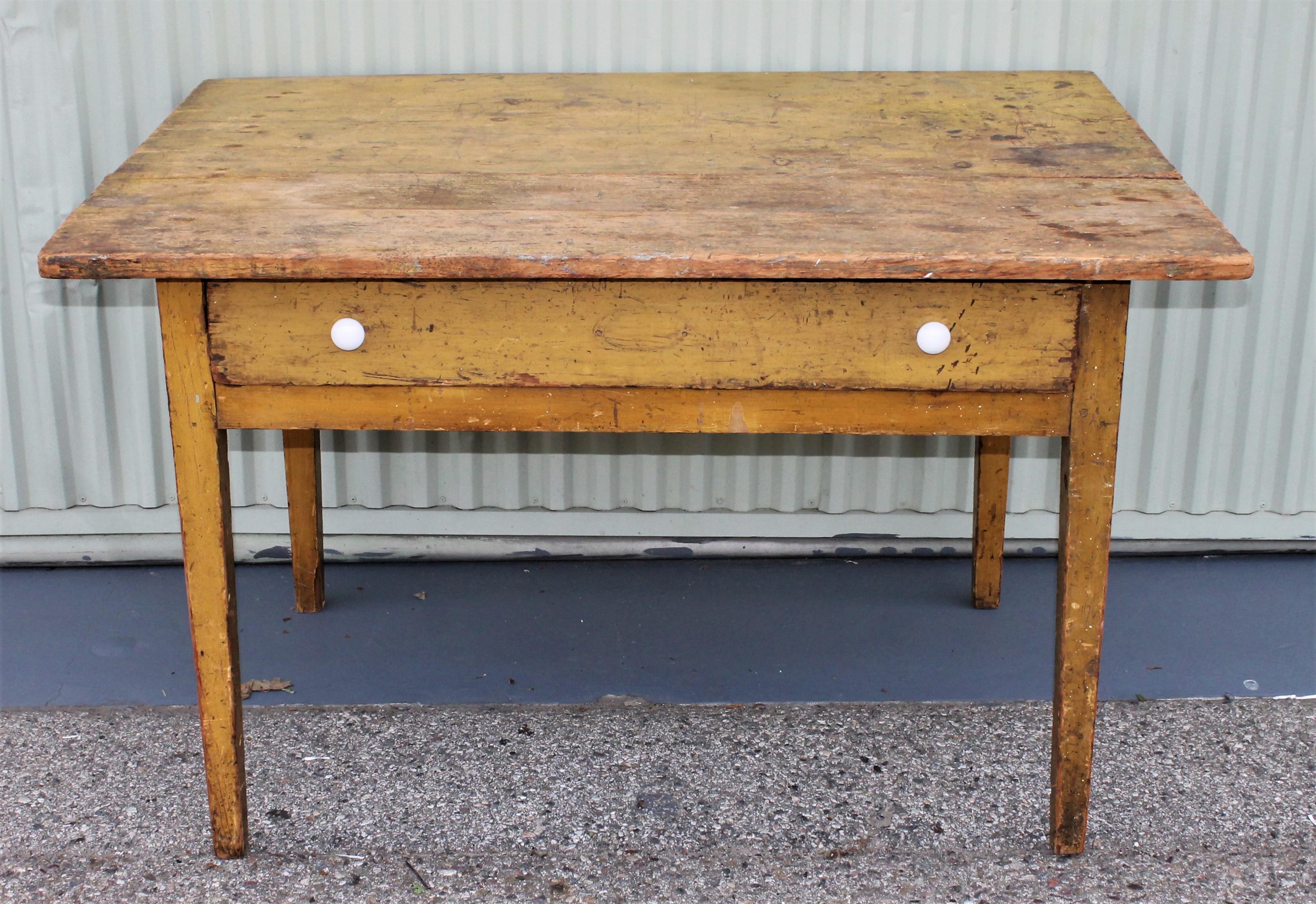 This 19th century original mustard painted farm table with large drawer. This table is square nail construction and original porcelain drawer pulls.