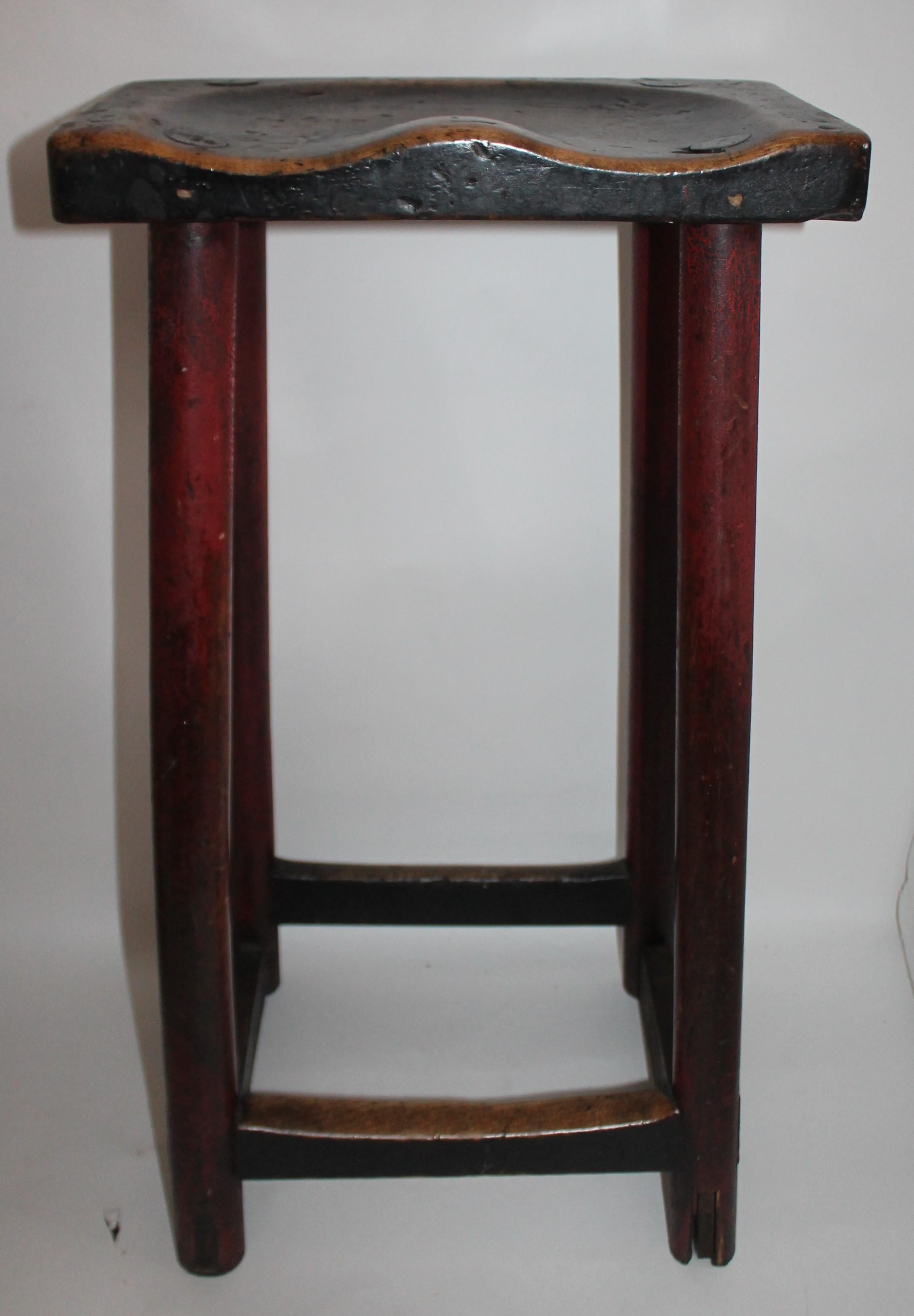 This amazing original red and black painted plank seat bar stool is in fine condition. This mortised and peg stool is sturdy and has a fine patina.