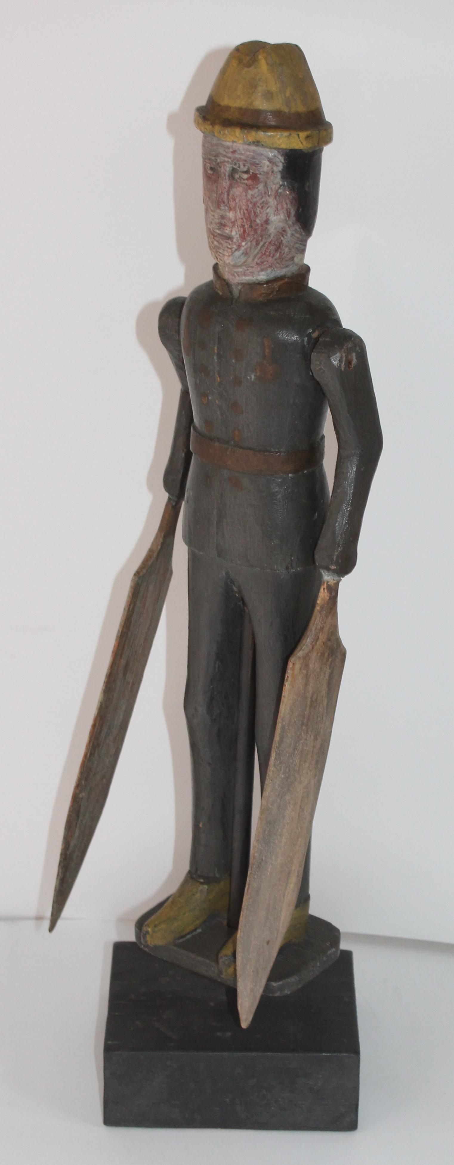 This amazing original painted folky whirlygig of a soldier is in good condition and on a block of wood that is its stand. The original blades have been re-glued at one time, but are also original to the piece. The carving is very crude with a nice