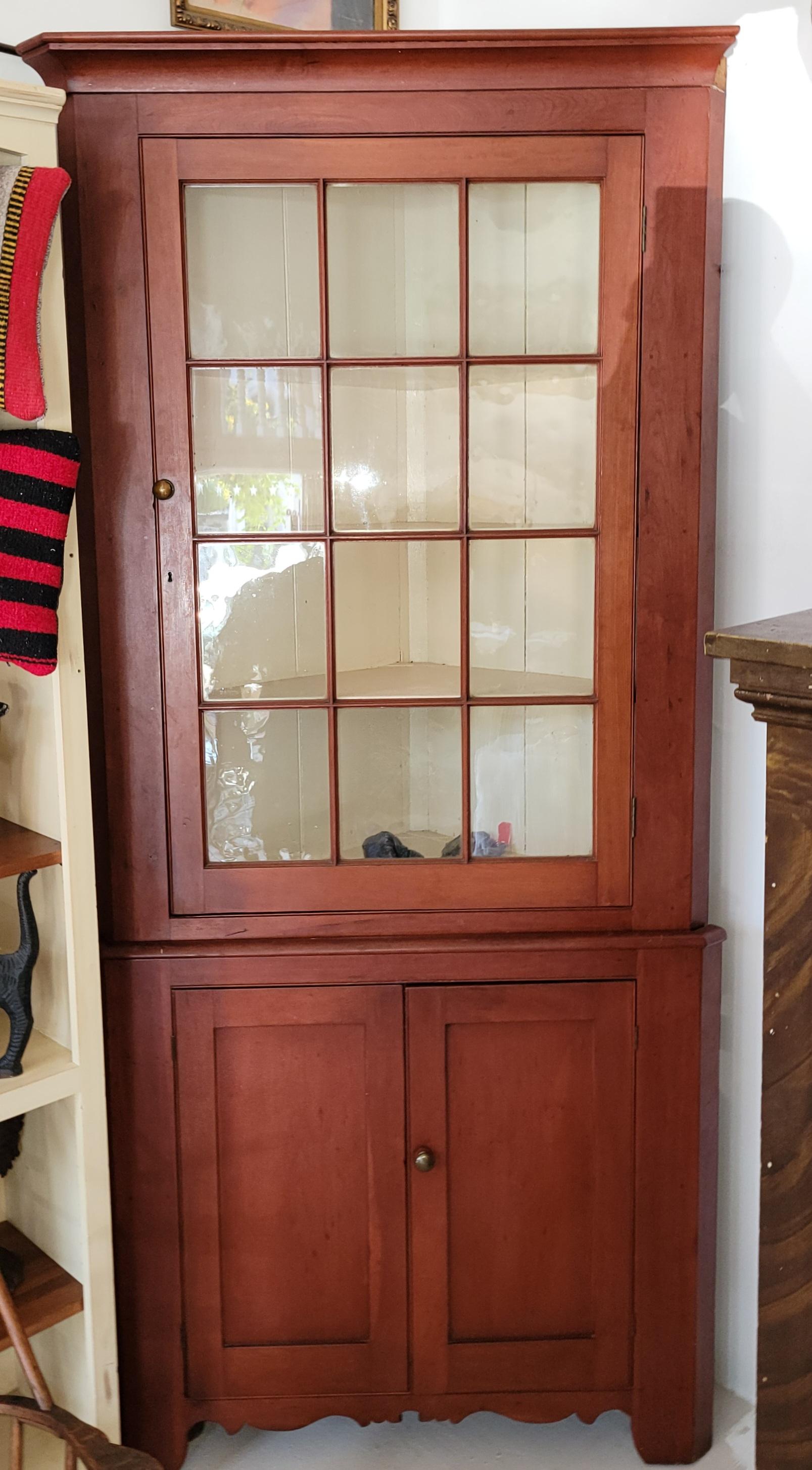 Esta fina y sencilla Pensilvania  dos piezas  original pintado de rojo  armario esquinero tiene doce cristales  cristales en la mitad superior del armario. El fondo es una base de puerta ciega.El estado es muy bueno y robusto.El interior del armario