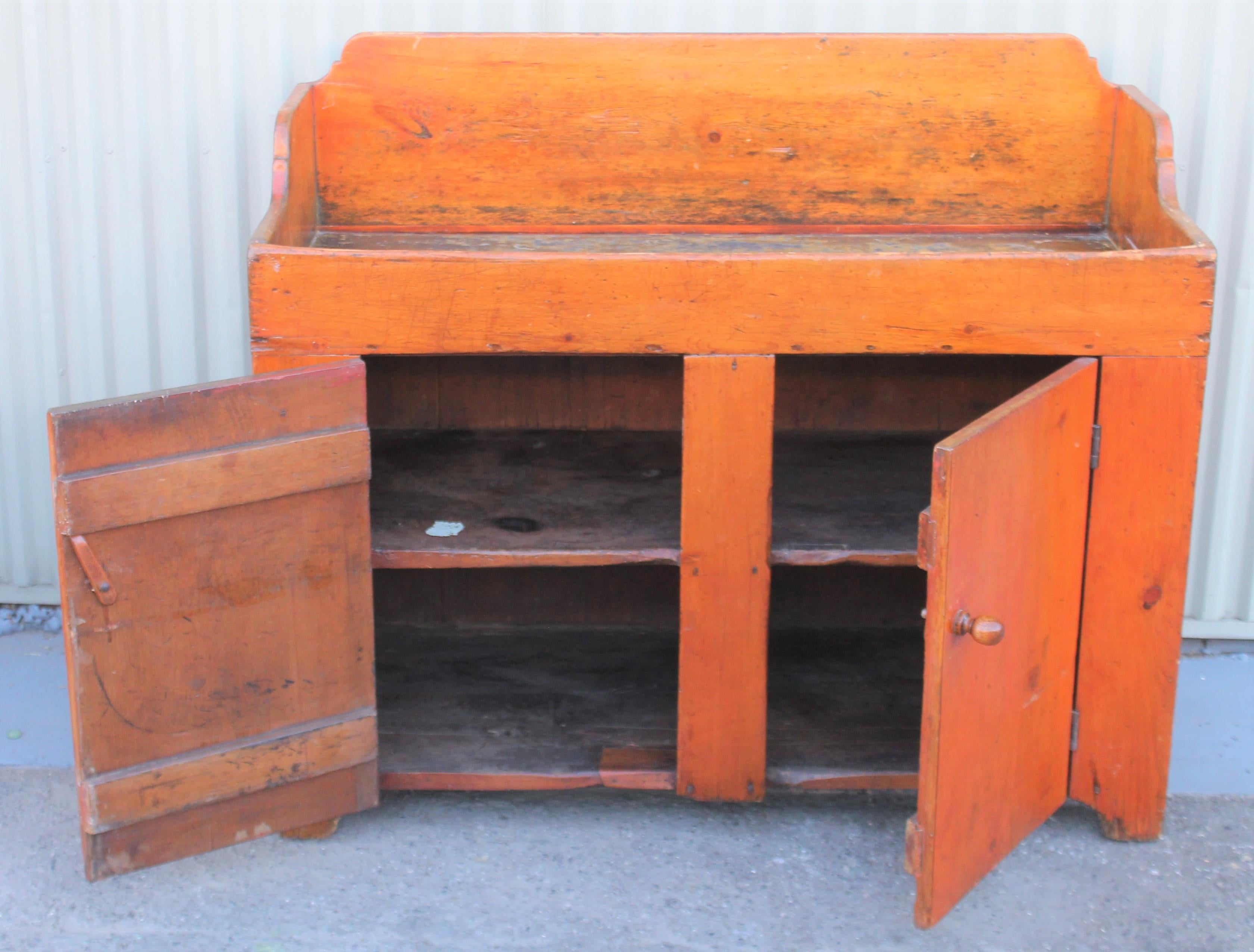 This fantastic dry sink is from Lancaster County, Pennsylvania and has two doors and two interior shelf's. The large mushroom pulls are original. The interior deep sink has a sage green original interior and was entire dry sink had a red wash on at