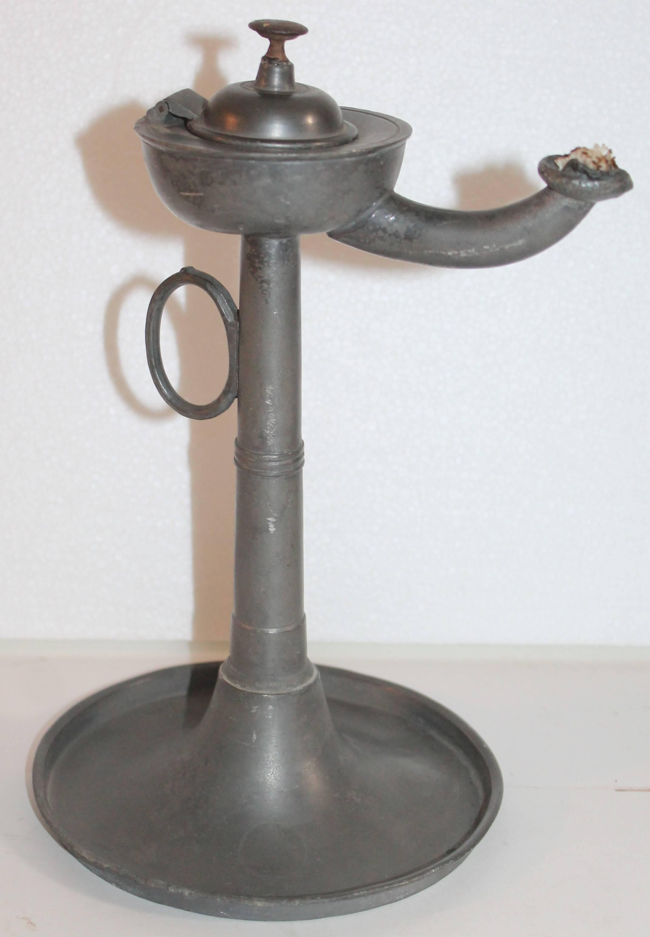 This fine pewter Betty or oil lamp is in fine condition. This oil lamp is quite unusual and has a iron pull on lid.