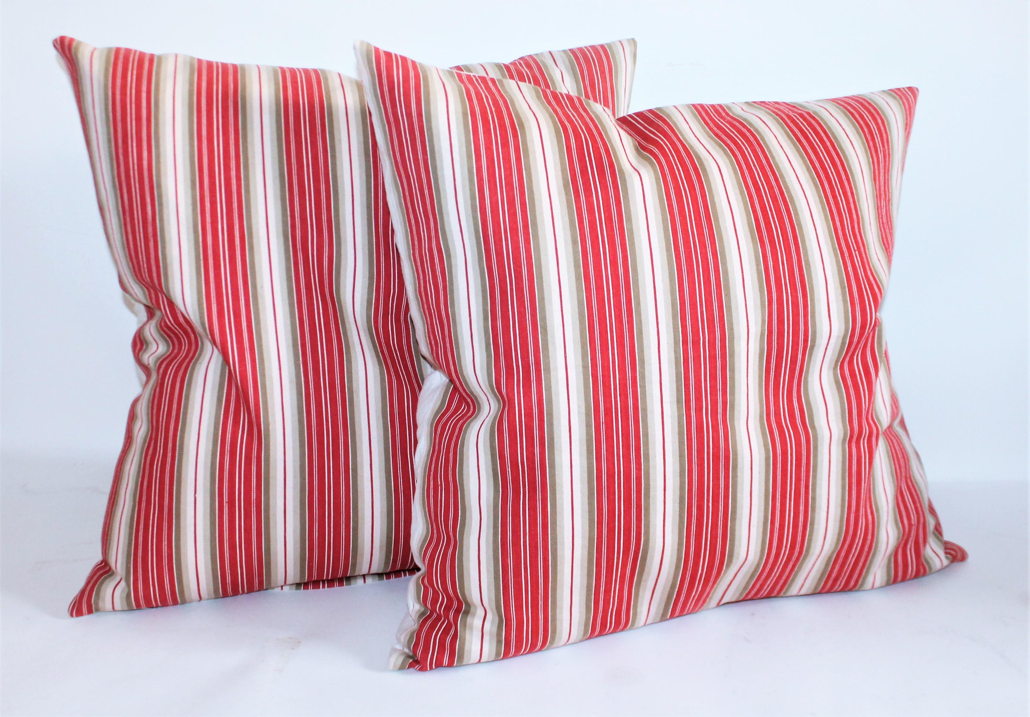 Larger striped pillows measure 22x 22 this red and tan wide stripe ticking is in fine condition and has cream cotton linen backings.
Smaller pillows measure 20 x 20 these dark cherry red wide stripe pillows and have a khaki tan wide stripe surround