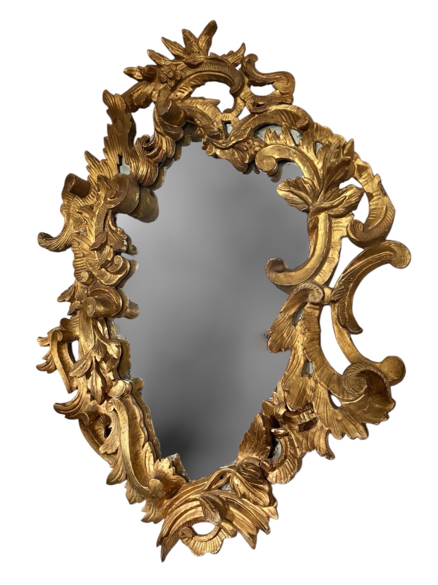A rococo giltwood oval mirror made in France in the 19th century. The oval mirror is elaborately carved with scrolled acanthus in deep relief.