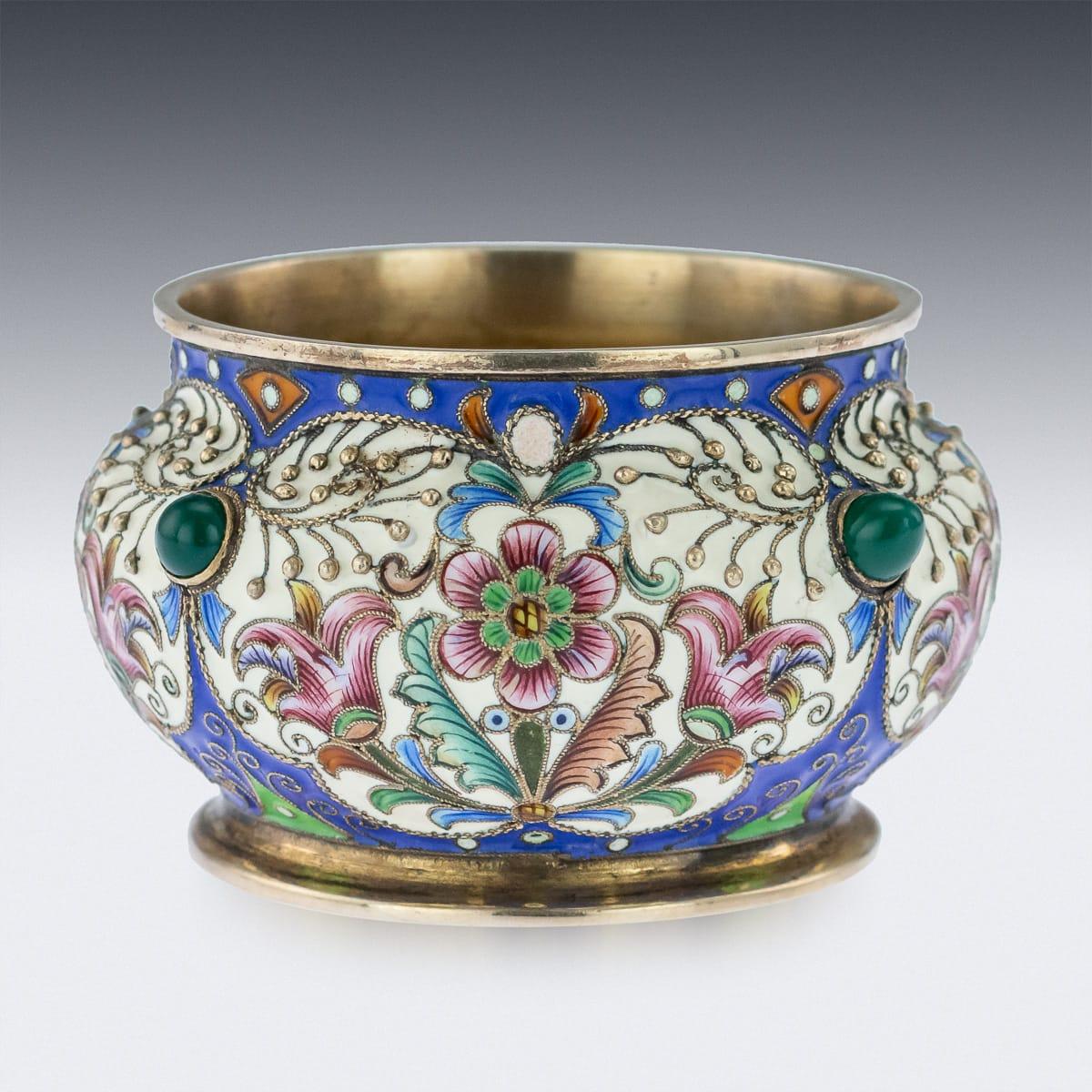 Antique late 19th century Imperial Russian solid silver and cloisonné enamel salt, of traditional shape, decorated with foliate forms with shaded reds, greens, blues, gentle pink and white enamels on gilded matted ground, set with cabochon emeralds.