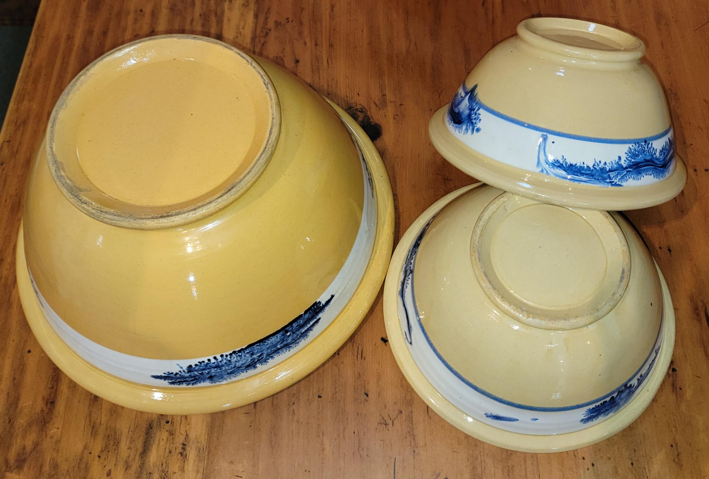 19th century yellow ware mixing bowls. Wonderful color with a white stripe going across the top and each has a beautiful blue design within the white stirpe. 
Bowls measure from largest to smallest.
Largest- 14 x 7
Middle- 11 x 5.25
Smallest - 10 x