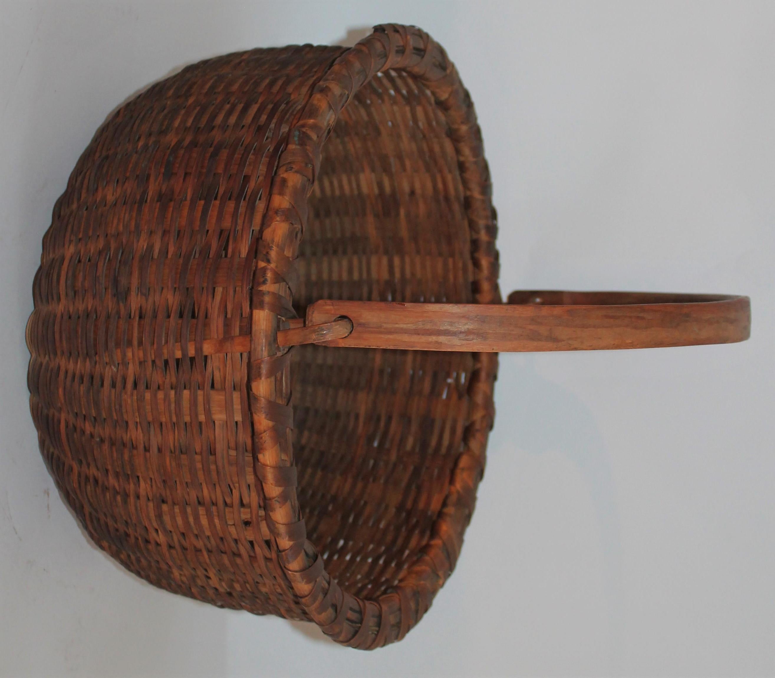 19th century handwoven basket from New England in a Shaker style format. The basket has the original kick up bottom and the original hand carved handle. The condition is pristine.