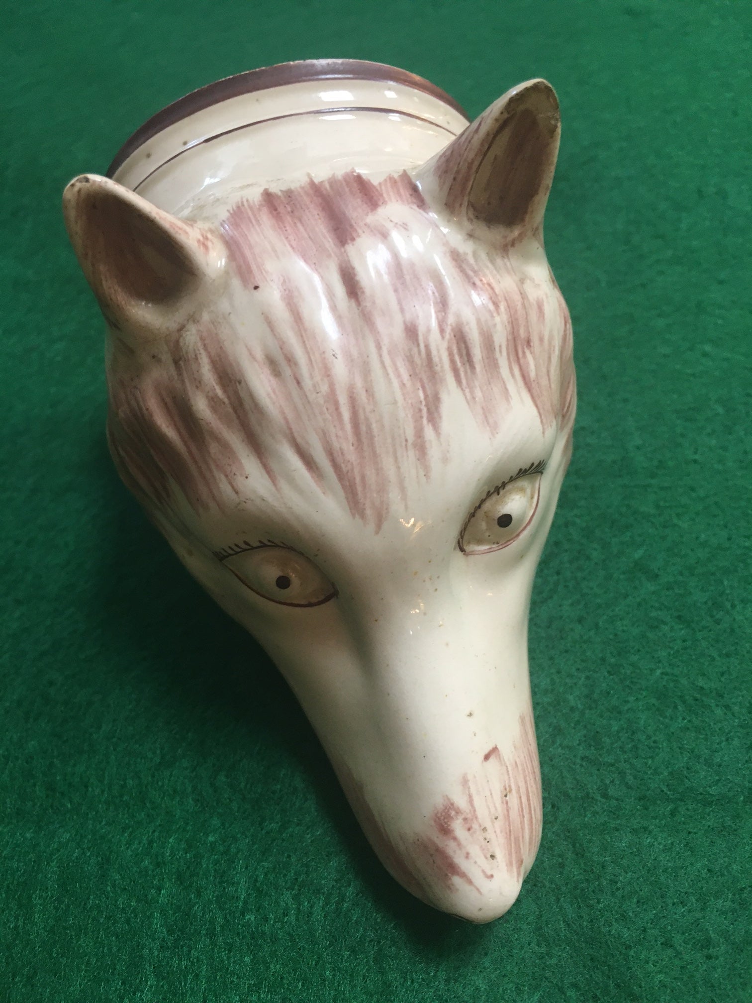 This charming early Staffordshire rare pale red fox stirrup cup features intaglio eyes outlined in black with exaggerated lashes, brownish red brush strokes and upright ears.  