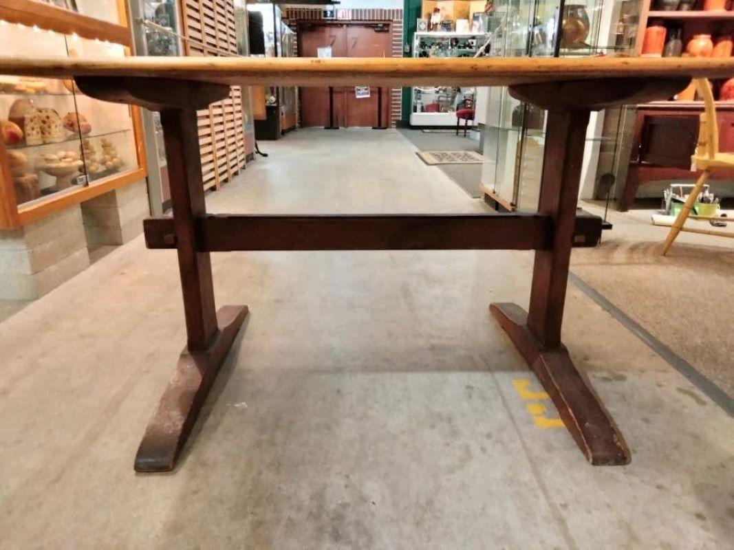 Early 20Thc hand crafted trestle table from Lancaster County,Pennsylvania.This table has a dark old wash on the base and fine wood peg construction. You can sit four or six at this table with great over hang top.