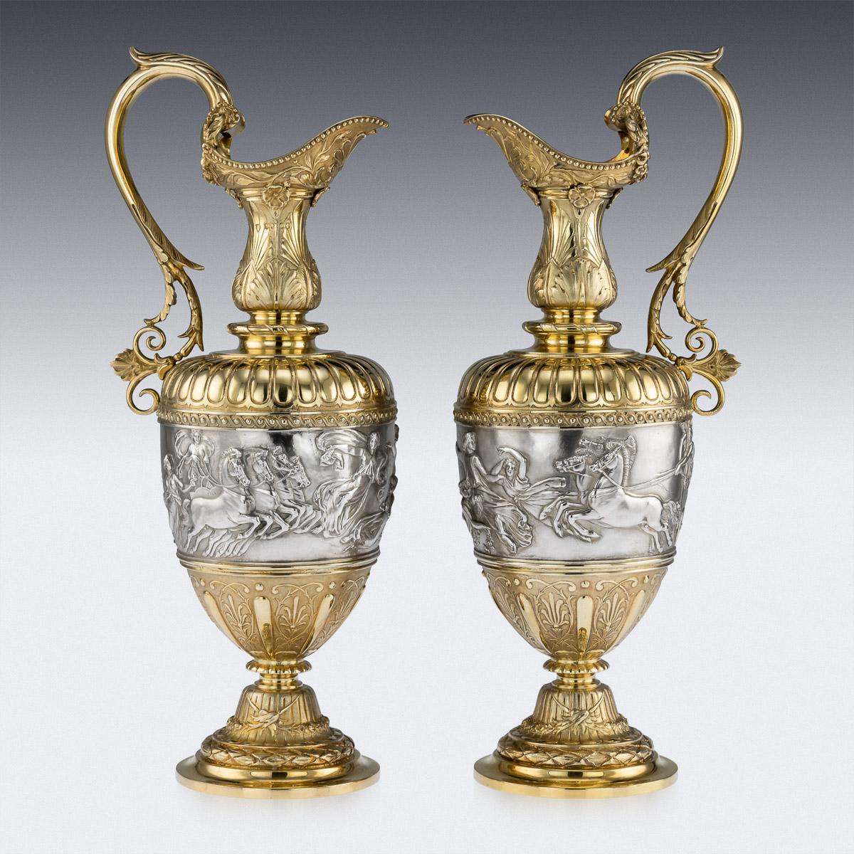 Antique 19th century Victorian magnificent pair of solid silver-gilt wine ewers. Amphora shaped, on a spreading foot chased with laurel leaf borders below fluted raised centre, the body with a large band figuring classical scenes of quadriga,