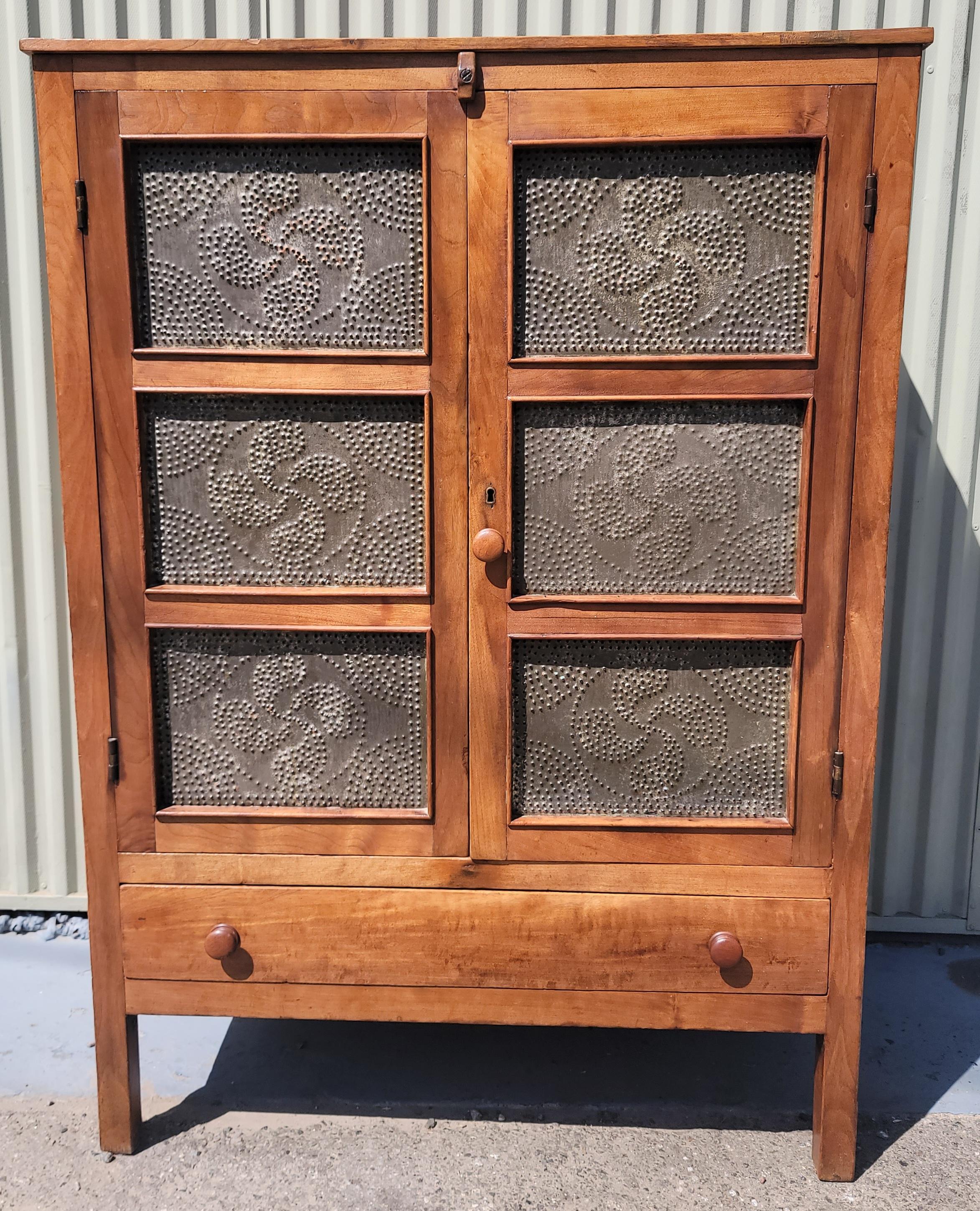 Amazing 19Thc Walnut pie safe with original punched pin wheel pattern tins.This fine hand made walnut pie safe has cut nail construction and wood pegs.The inside shelf's  have a nice mellow patina and a light coat of wax or varnish.Amazing picture