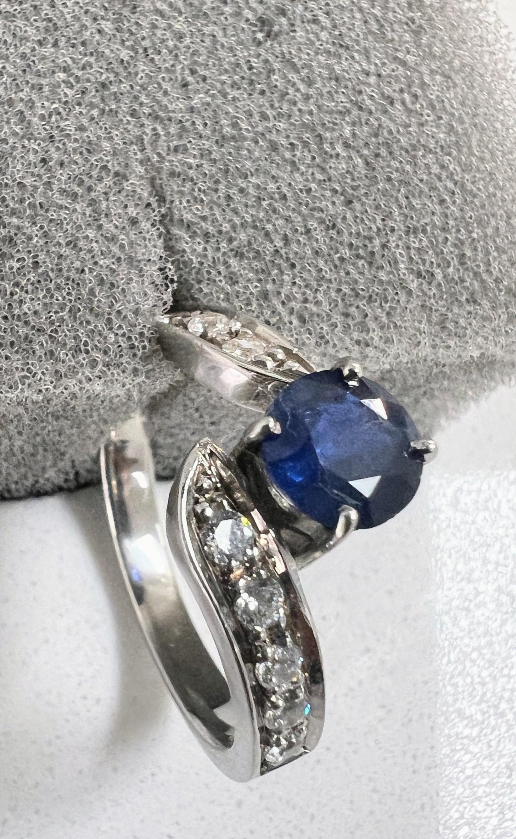 Erhöhen Sie Ihre Liebesgeschichte mit unserem bezaubernden Ring mit einem blauen Saphir von 1 Karat, umgeben von einem schimmernden Halo aus strahlend weißen Saphiren auf beiden Seiten. 

Wesentliche Merkmale:
Geschmückt mit einem atemberaubenden