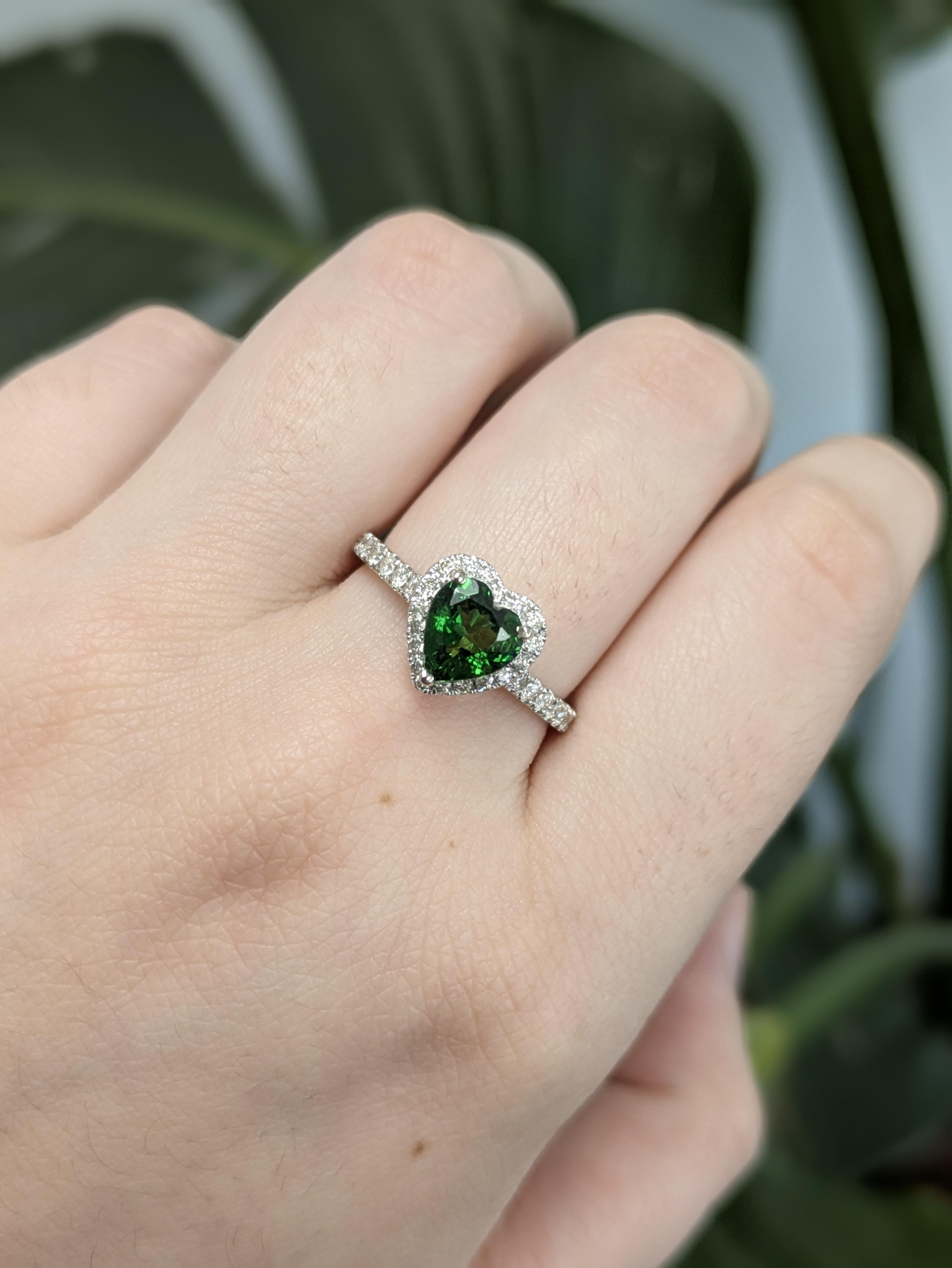 Questo affascinante anello presenta un granato Tsavorite a forma di cuore di 1,00ct proveniente dalla Tanzania, che misura 7,1 x 6,6 mm. Incastonata in oro 14k (2,41g), la gemma verde è circondata da 44 diamanti scintillanti per un totale di