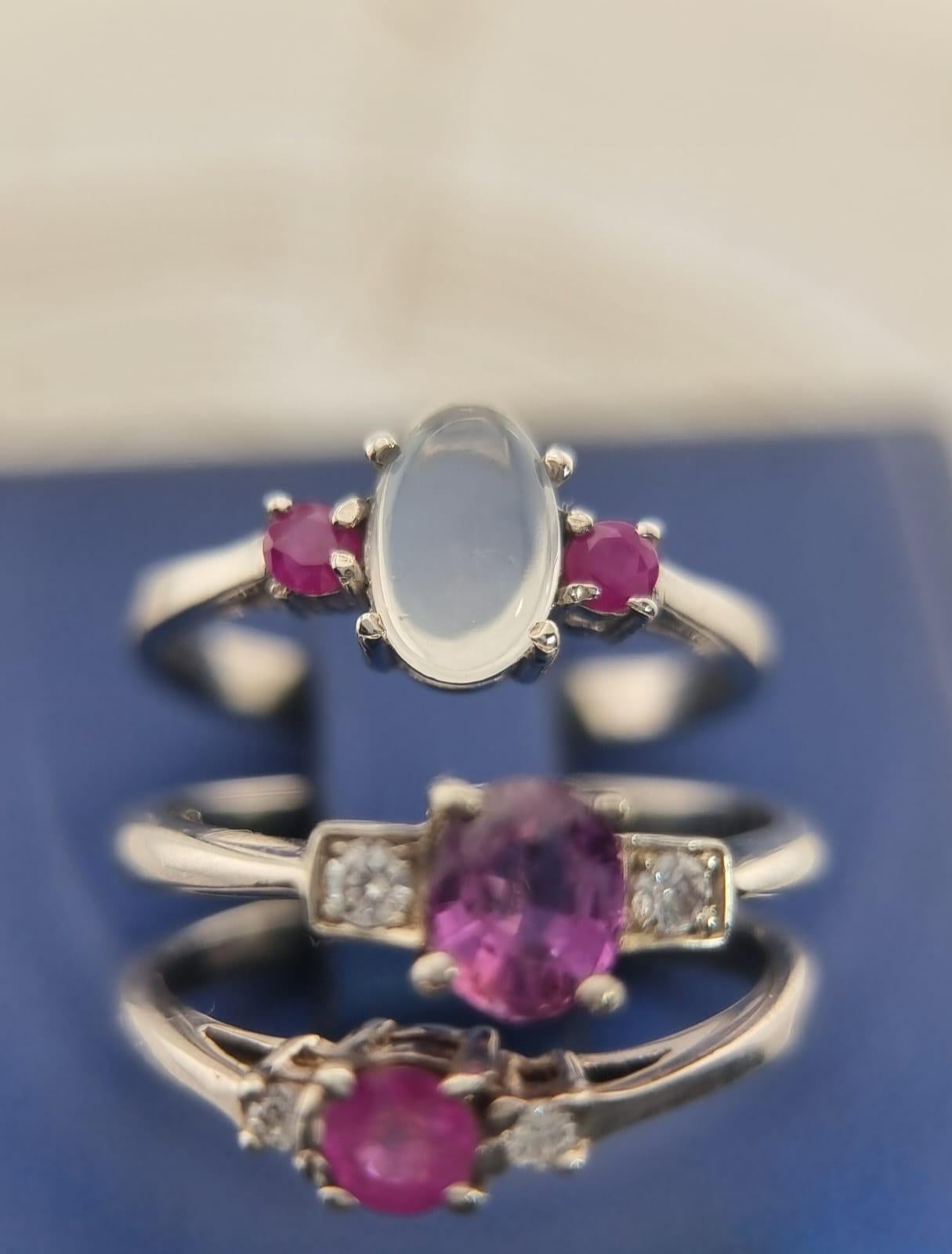 Indulge in the celestial charm of our exquisite Natural 1ct Moonstone and Ruby Cocktail Ring. At the heart of this enchanting piece lies a captivating 1ct cabochon moonstone, Flanked by two sumptuous .75ct oval rubies, this ring is a symphony of
