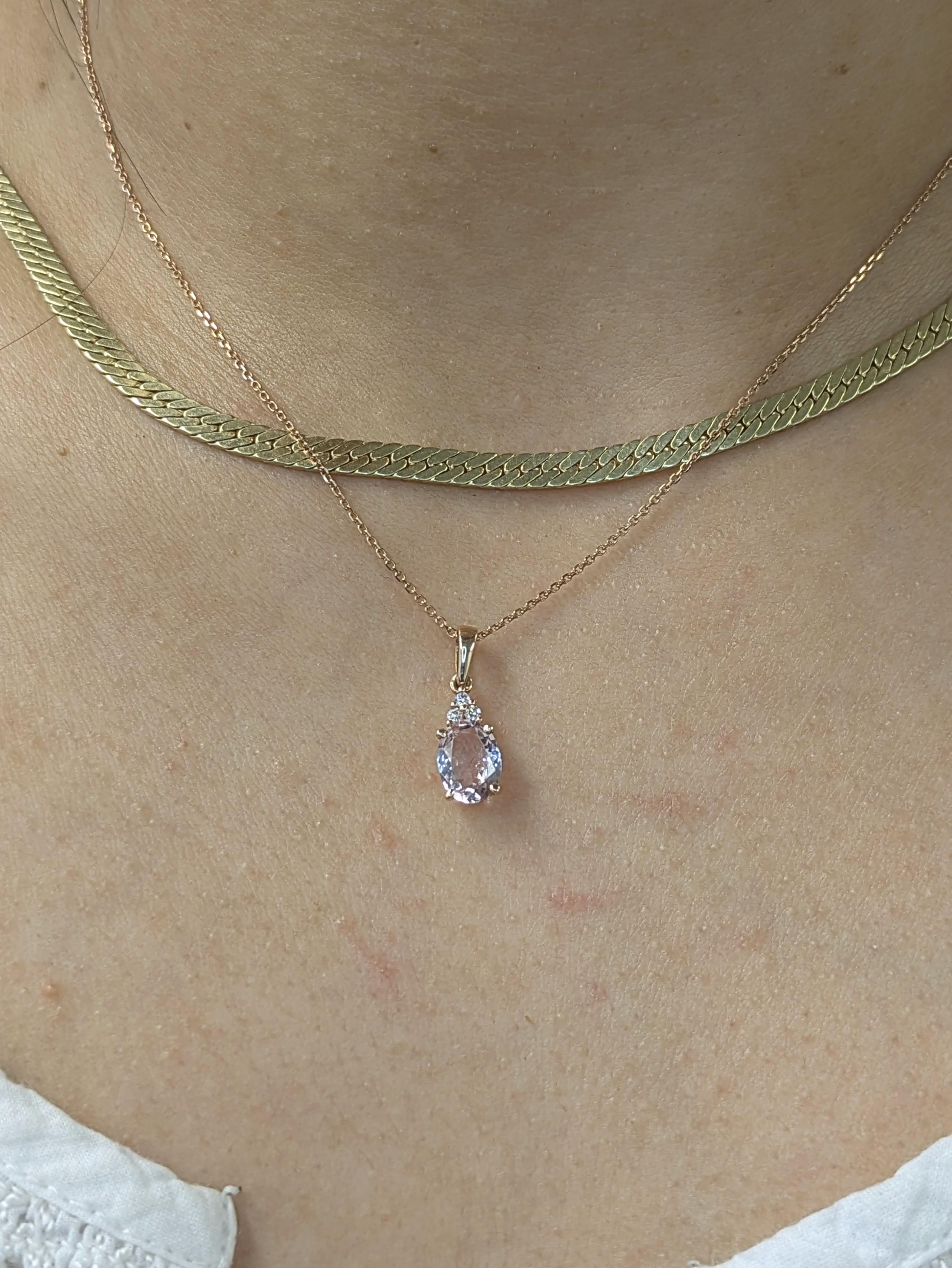 Elegante e sofisticato, questo ciondolo in oro massiccio 14k mette in mostra una splendida morganite ovale da 1 carato con tre sottili accenti di diamanti per un maggiore splendore. Il design a scorrimento gli conferisce un look pulito e moderno,