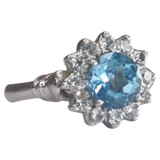 Te presentamos nuestro Anillo de Plata y Platino con Topacio Azul Natural Redondo de 1 ct, una pieza impresionante que irradia elegancia y sofisticación. Este anillo tiene en el centro un fascinante Topacio Redondo de 1 ct, conocido por su