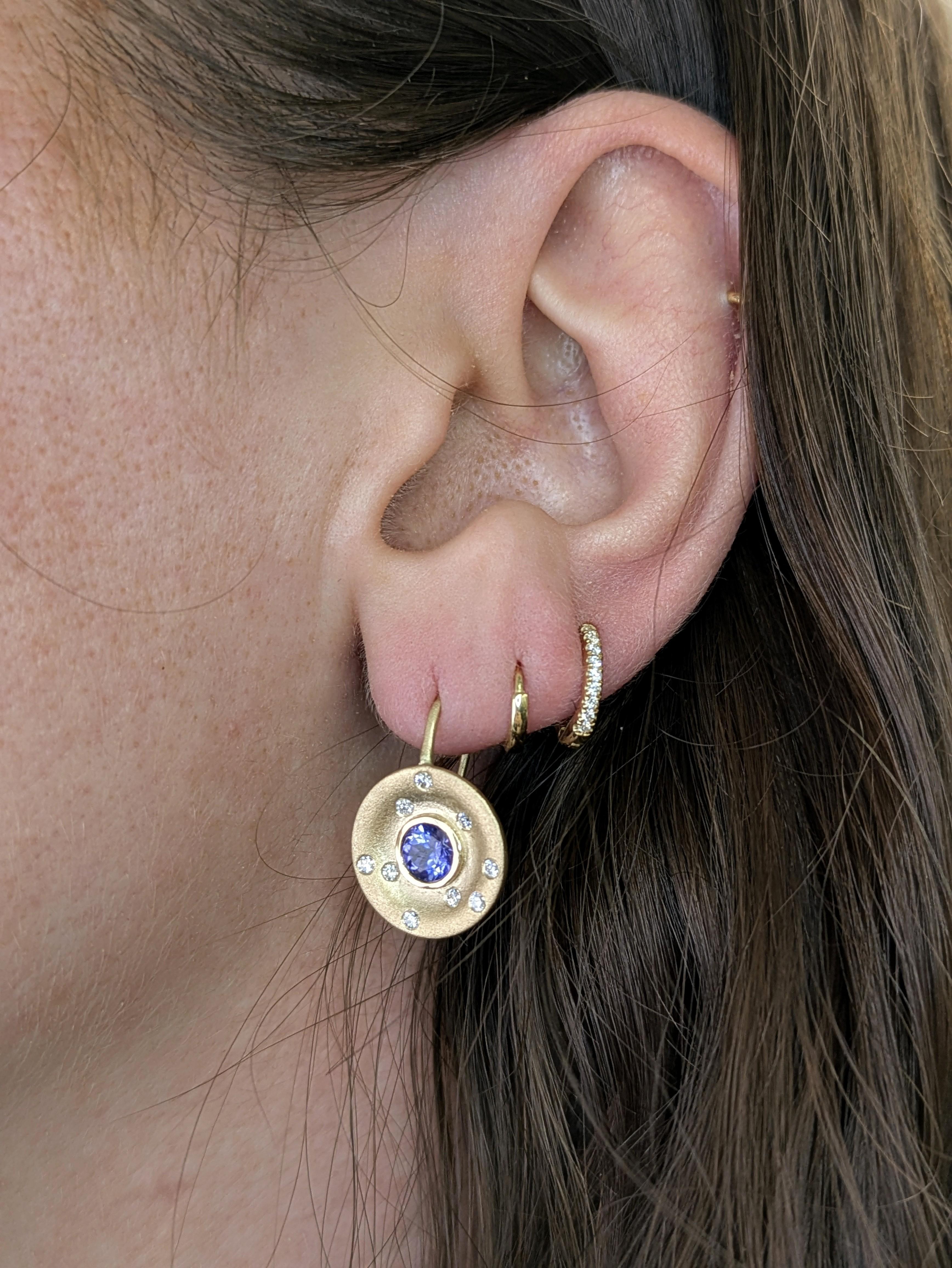 Crafted in solid 14K matte yellow gold, these stylish clip-on earrings feature 4mm round tanzanites (1.04 carat total) in a sleek bezel setting. Earth-mined diamond accents are subtly flush-set, enhancing their starlit-inspired look with a