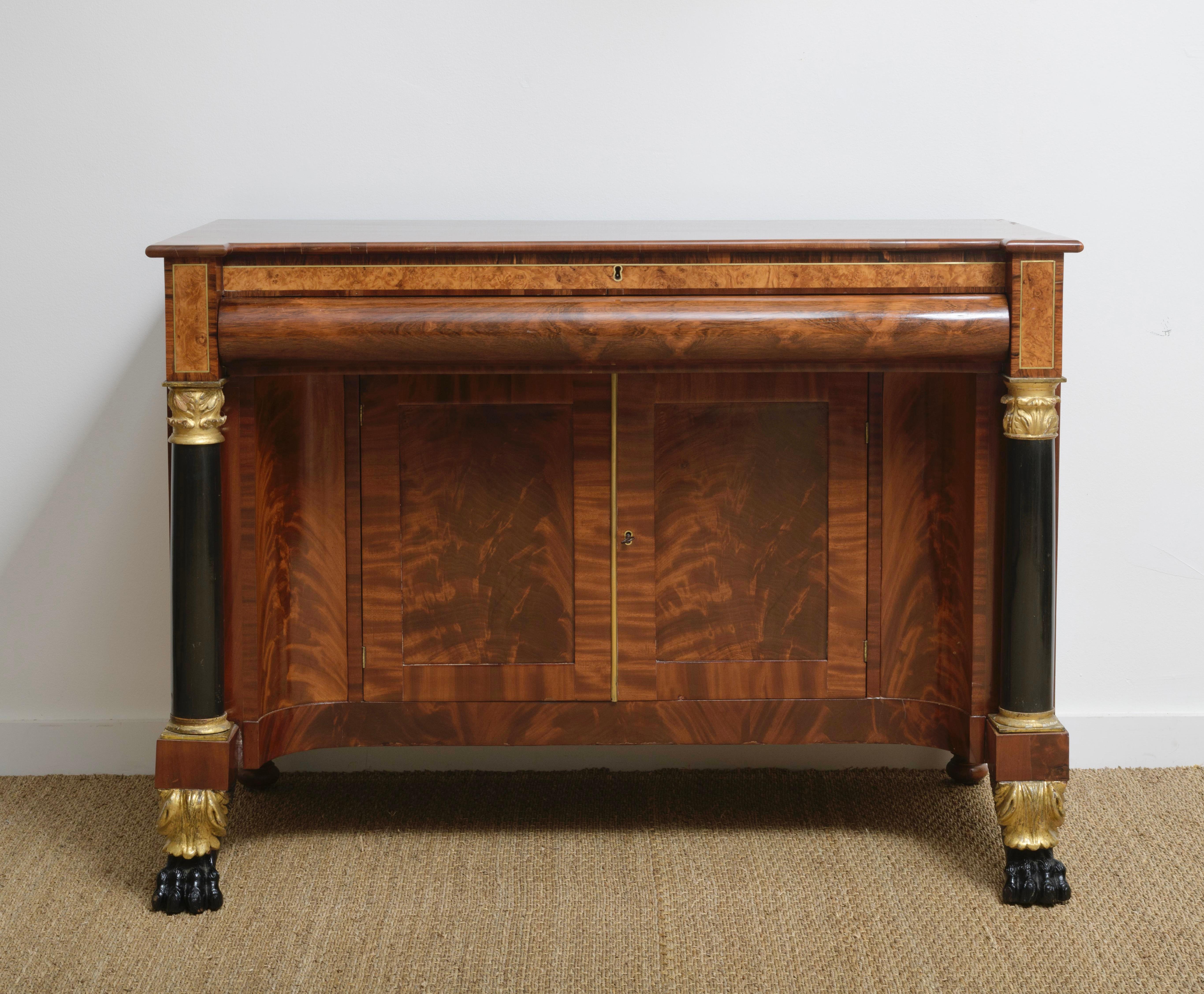 Unusual 1st Empire desk,  circa 1810, in mahogany, Burl, with Brass inlay and blackened columns ending on 2 blackened lion's feet above gilded leaves . 
Center drawer pulls out to reveal hinged writing surface with fitted drawer.  All above a curved