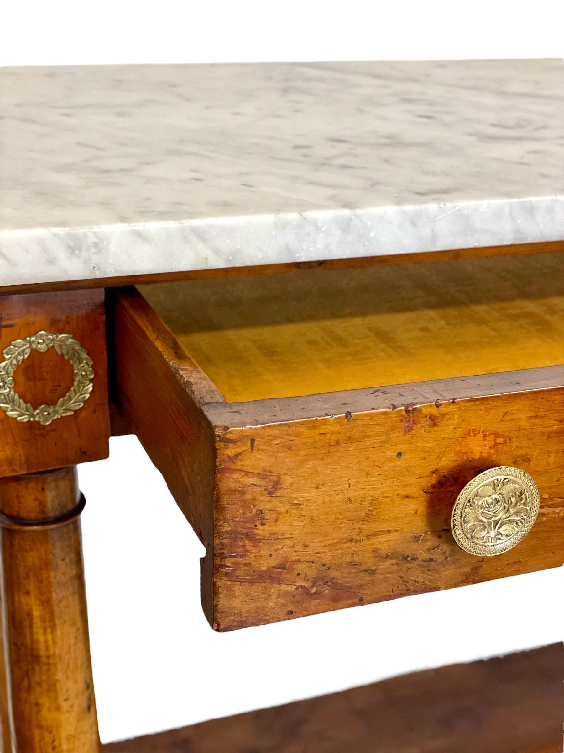 An imposing 1st Empire period console table of impressive proportions, featuring a veneered wood body and a grey veined marble top. The marble tray is set over one long frieze drawer, complete with ornate circular brass 'rosebud' drawer pulls, while