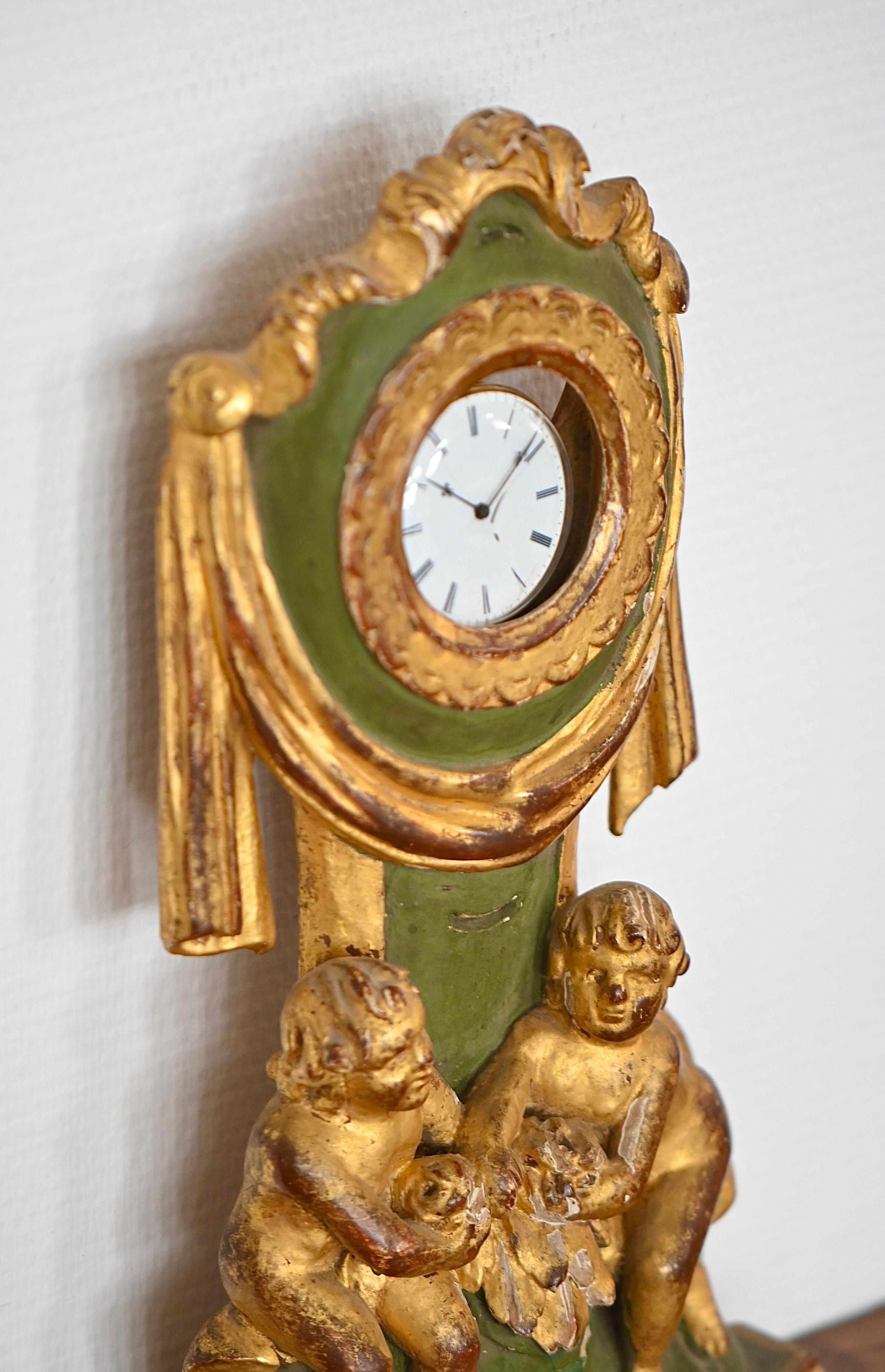 Scopri un eccezionale oggetto da collezione: questo portaorologi in legno dorato, un vero tesoro risalente al primo Impero. Combinando eleganza e storia, si distingue per il suo fascino antico e i suoi squisiti dettagli. Il legno, parzialmente