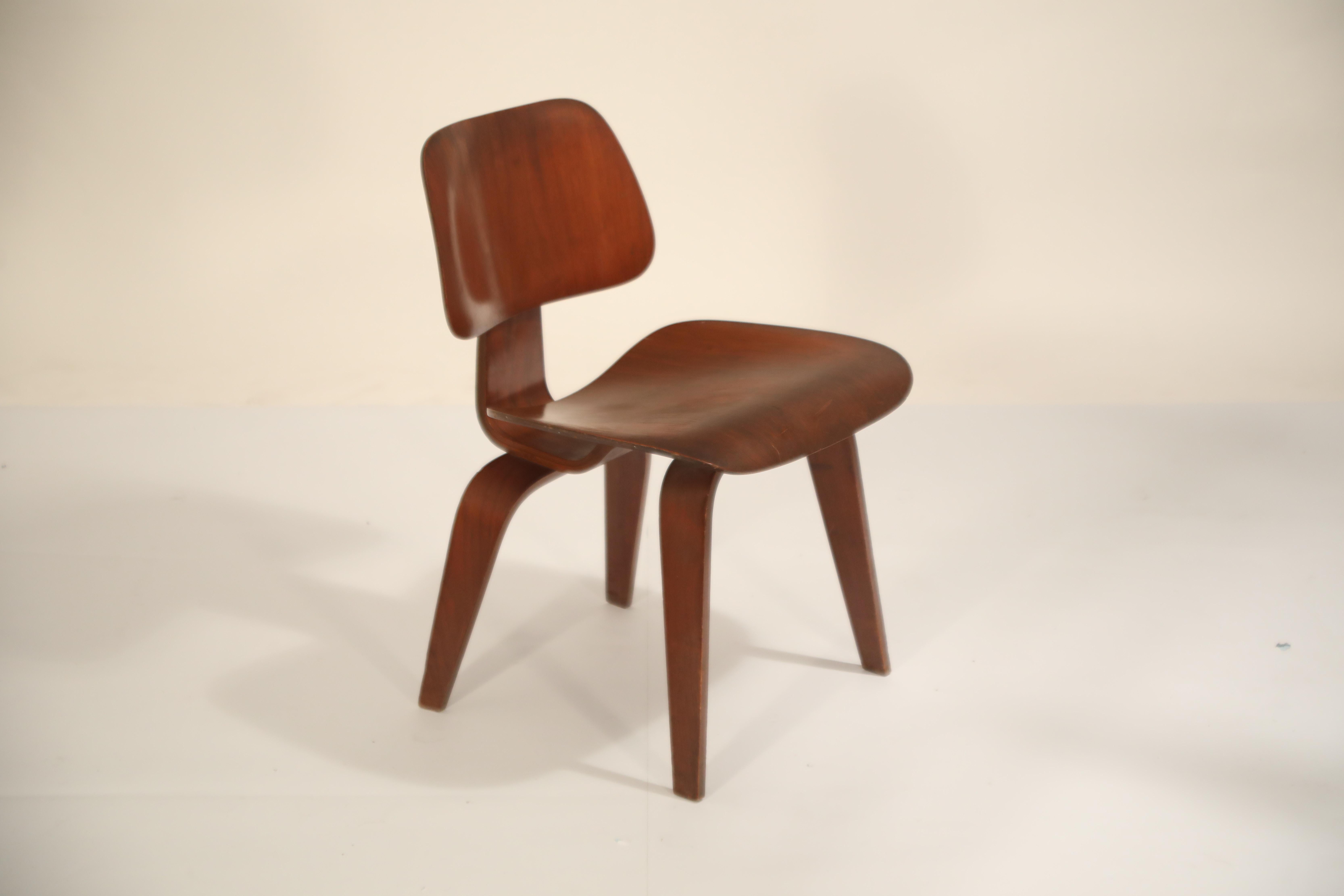 This incredible signed collector's piece is a 1st Generation DCW (Dining Chair Wood) Chair by Charles and Ray Eames, manufactured by Evans Products Company and distributed by Herman Miller. The two part label underneath the chair displays both Evans