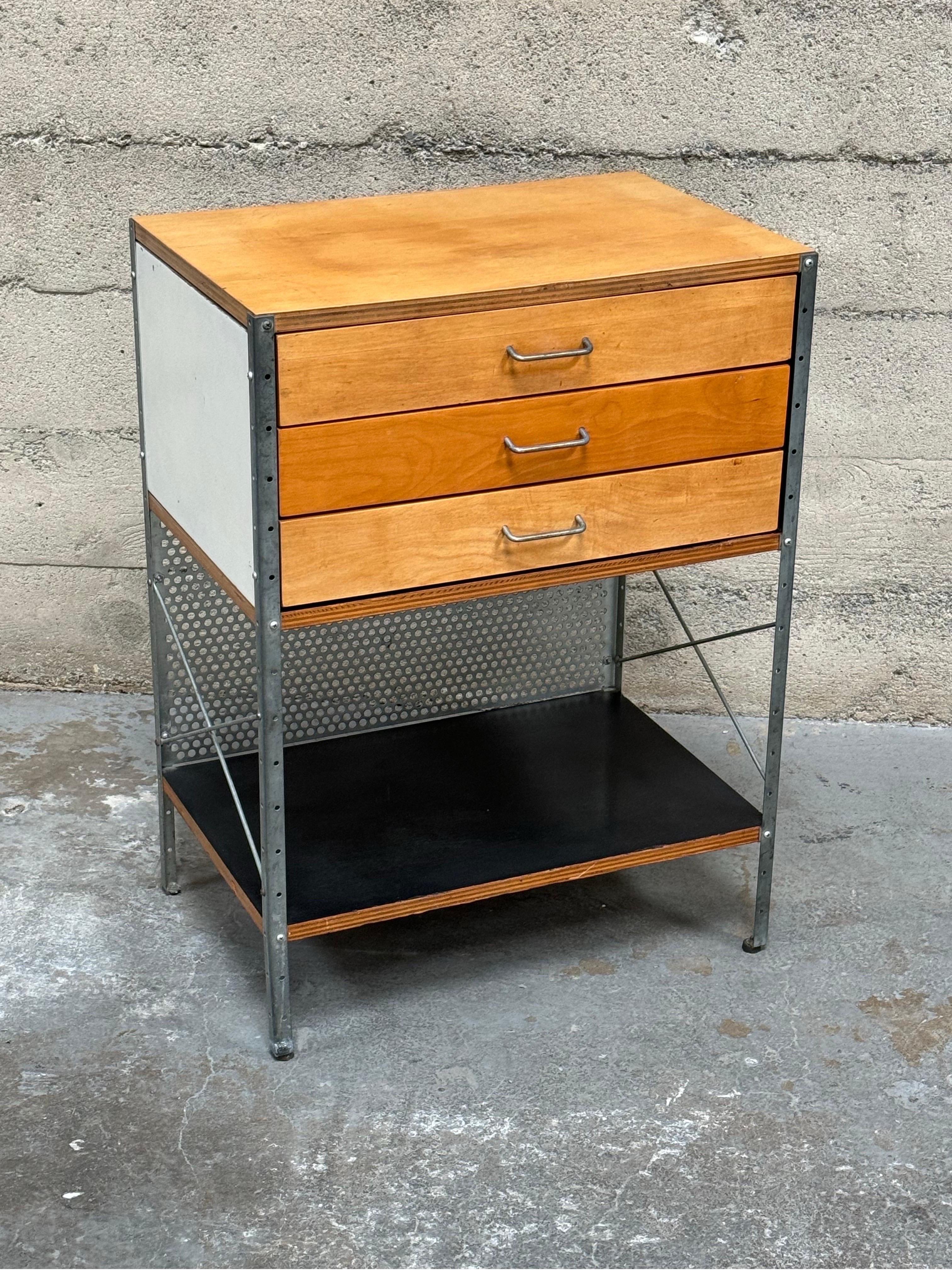 1st Generation Eames ESU (Eames Storage Unit) this is called the 270-N series. It's constructed of birch, plywood, lacquer and steel and has three pull drawers with a bottom shelf. The sides are colored panels in gray, white and black. The bottom