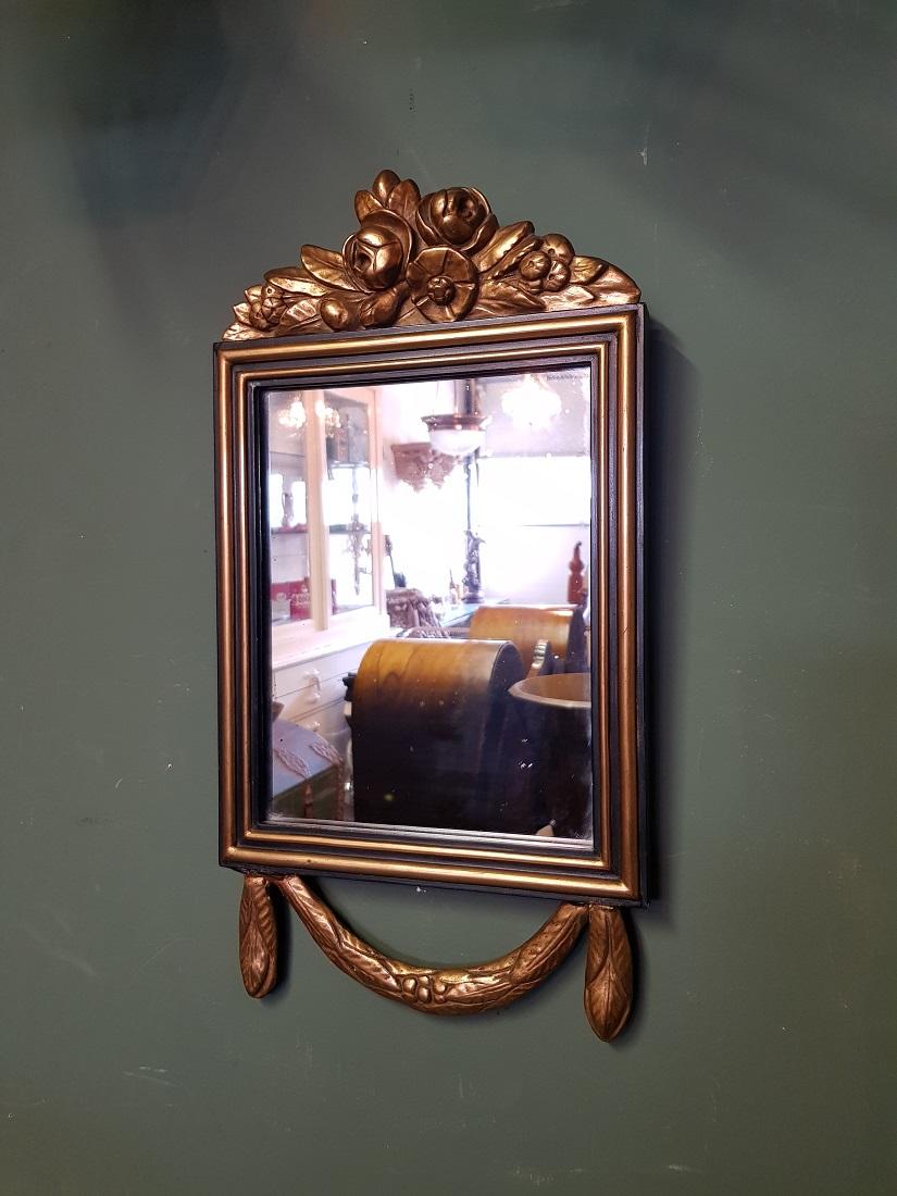 Classic mirror in Louis XVI style with partly blackened and gilt frame, the mirror has a few weather spots and a small restoration to a cone below, this was made by frame maker L.F. Reeker from Amsterdam located at the P.C. Hooftstraat (RKD).
