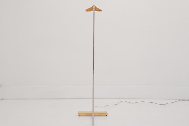 This is a 1UWV low profile, brass and chrome floor swivel lamp by Cedric Hartman. This floor lamp is a perfect blend of beauty, simplicity, and function. The base and shade are polished brass. The stem is chrome. The shade is a roof shape and the