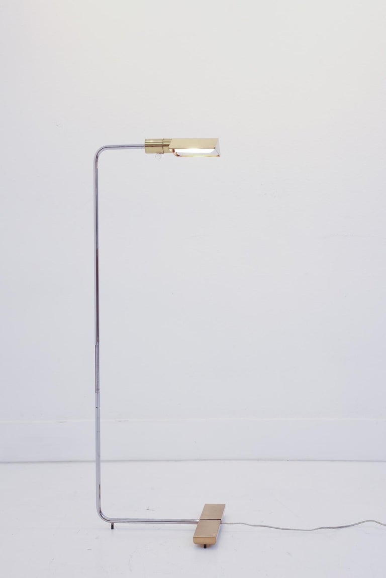 This is a 1UWV low profile, brass and chrome floor swivel lamp by Cedric Hartman. This floor lamp is a perfect blend of beauty, simplicity, and function. The base and shade are lacquered brass. The stem is chrome. The shade is a roof shape and the
